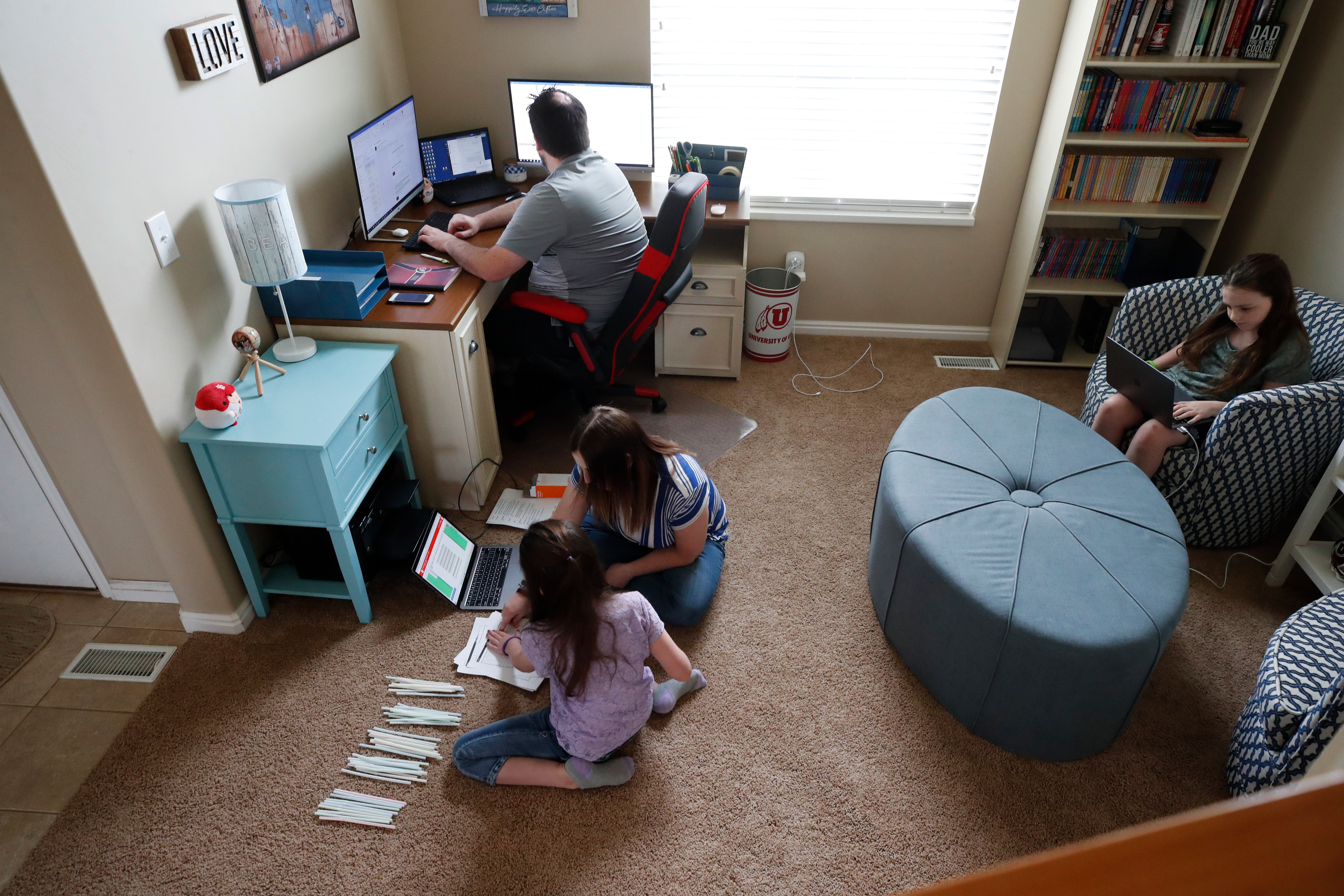 Students during remote learning classes with the help of their mother while their father works from home in West Jordan, Utah.
