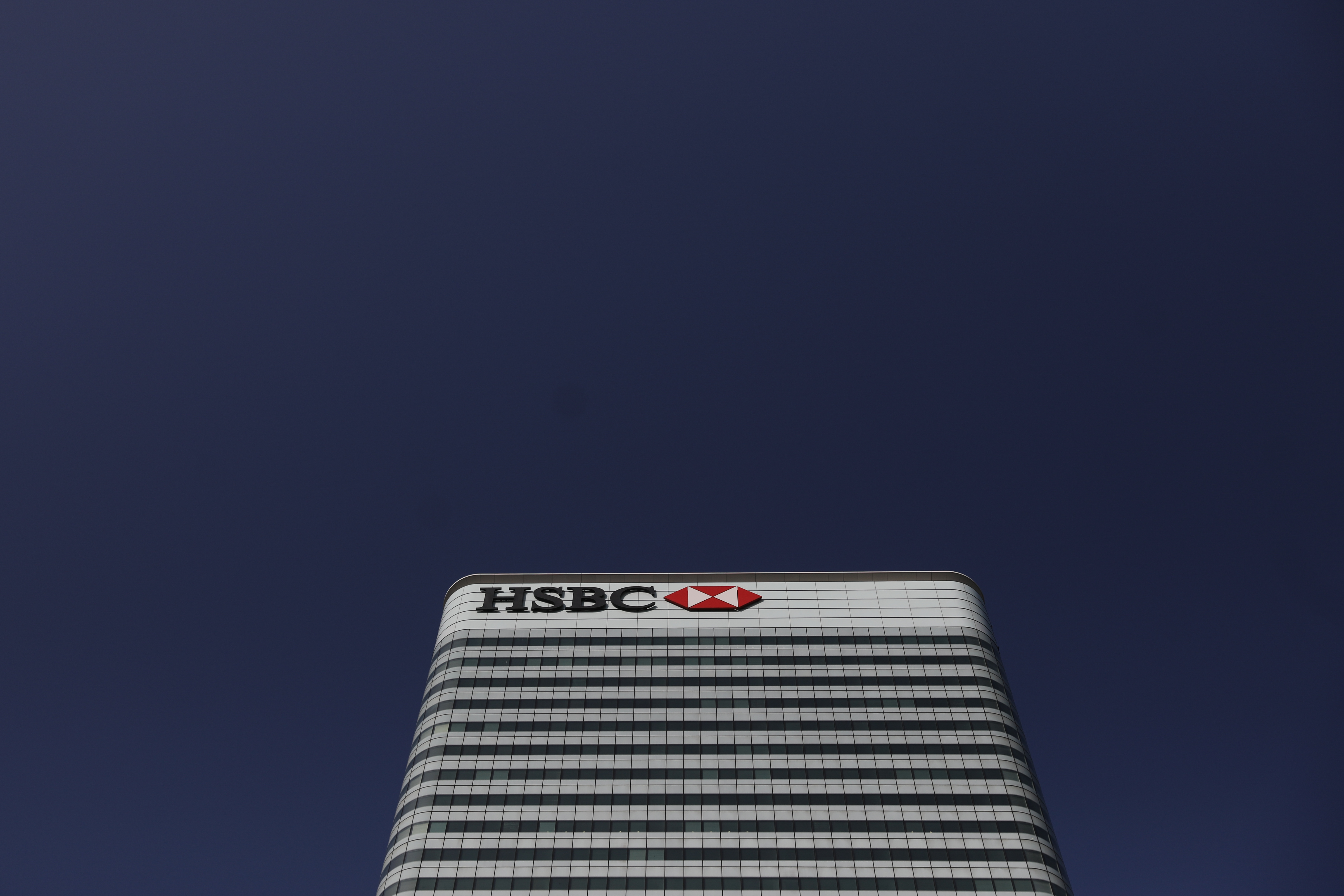 A sign sits on the HSBC Holdings Plc headquarters office building in the Canary Wharf business, financial and shopping district of London, U.K., on Friday, Sept. 18, 2020. After a pause during lockdown, lenders from Citigroup Inc. to HSBC Holdings Plc have restarted cuts, taking gross losses announced this year to a combined 63,785 jobs, according to a Bloomberg analysis of filings. Photographer: Simon Dawson/Bloomberg via Getty Images