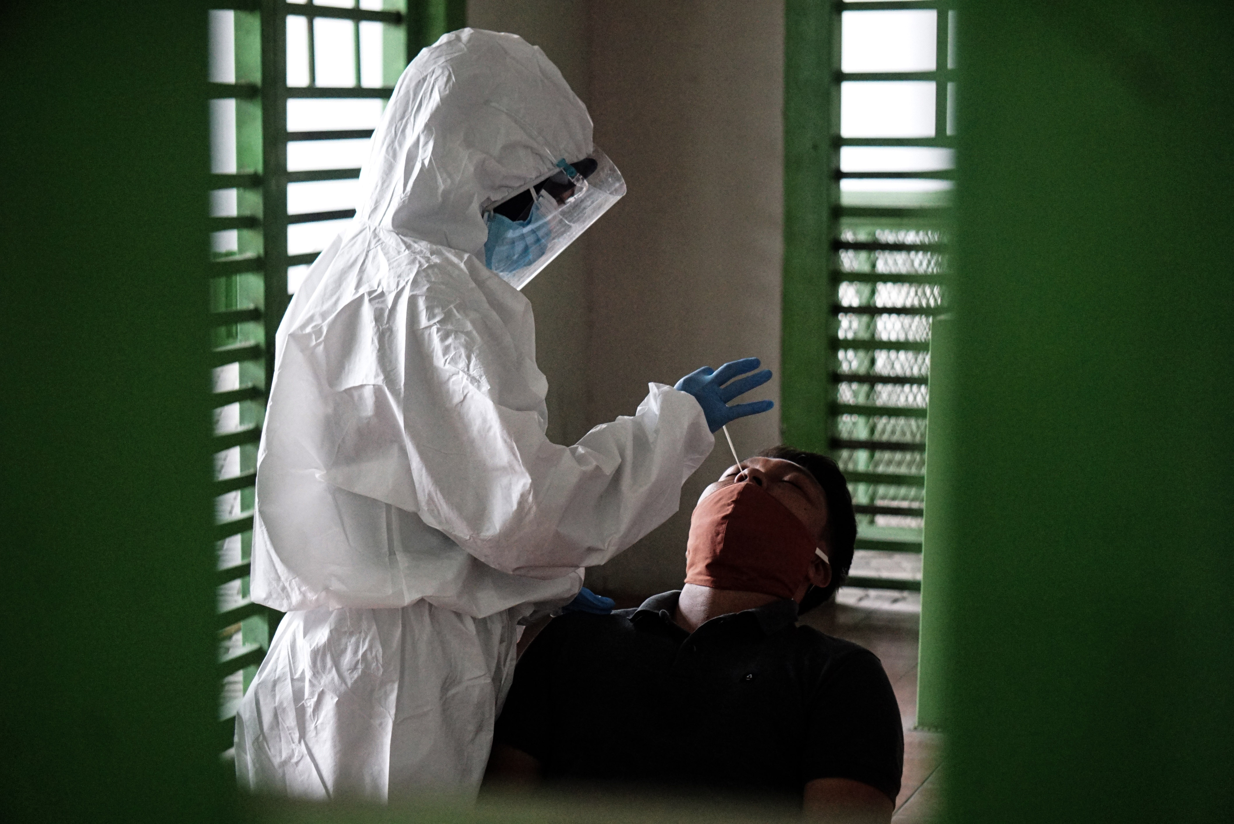 BEKASI, Sept. 24, 2020 -- A medical worker in protective suit collects swab samples from a man amid the COVID-19 outbreak in Bekasi, West Java, Indonesia, Sept. 24, 2020. (Photo by Arya Manggala/Xinhua via Getty) (Xinhua/Arya Manggala via Getty Images)