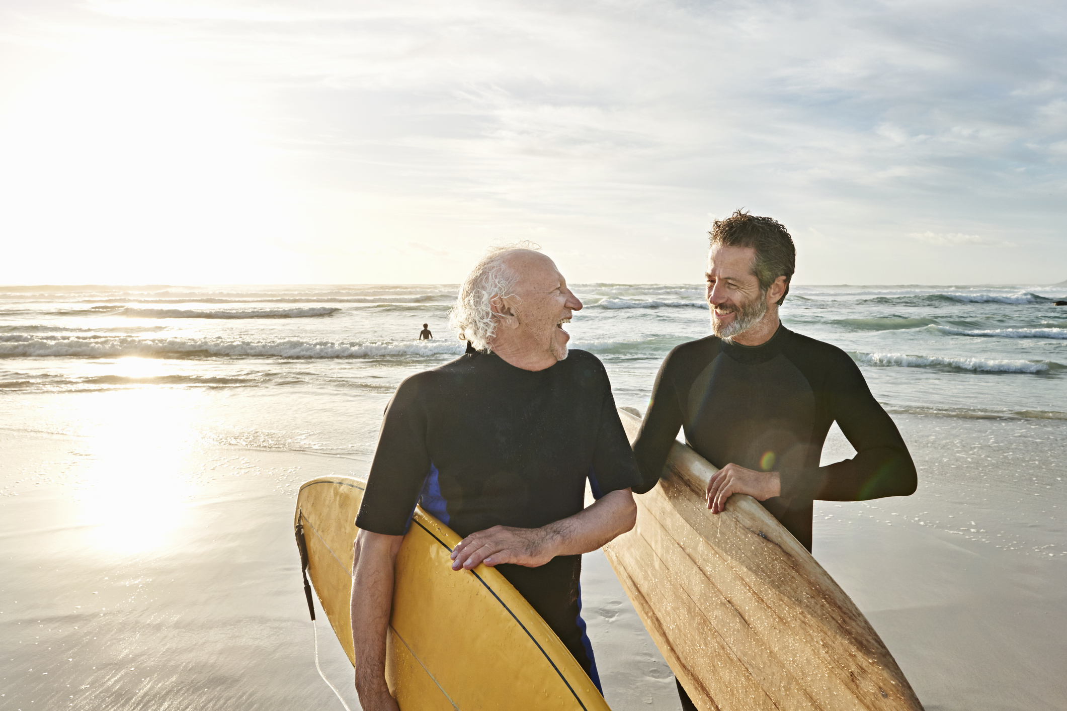 Father and his adult son on a beach with matching surf boards.