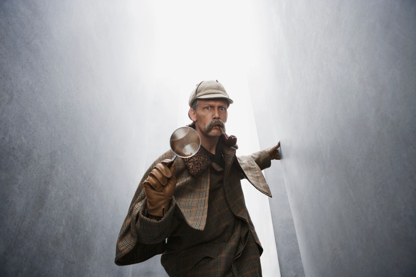 A man dressed like Sherlock Holmes holding a magnifying glass