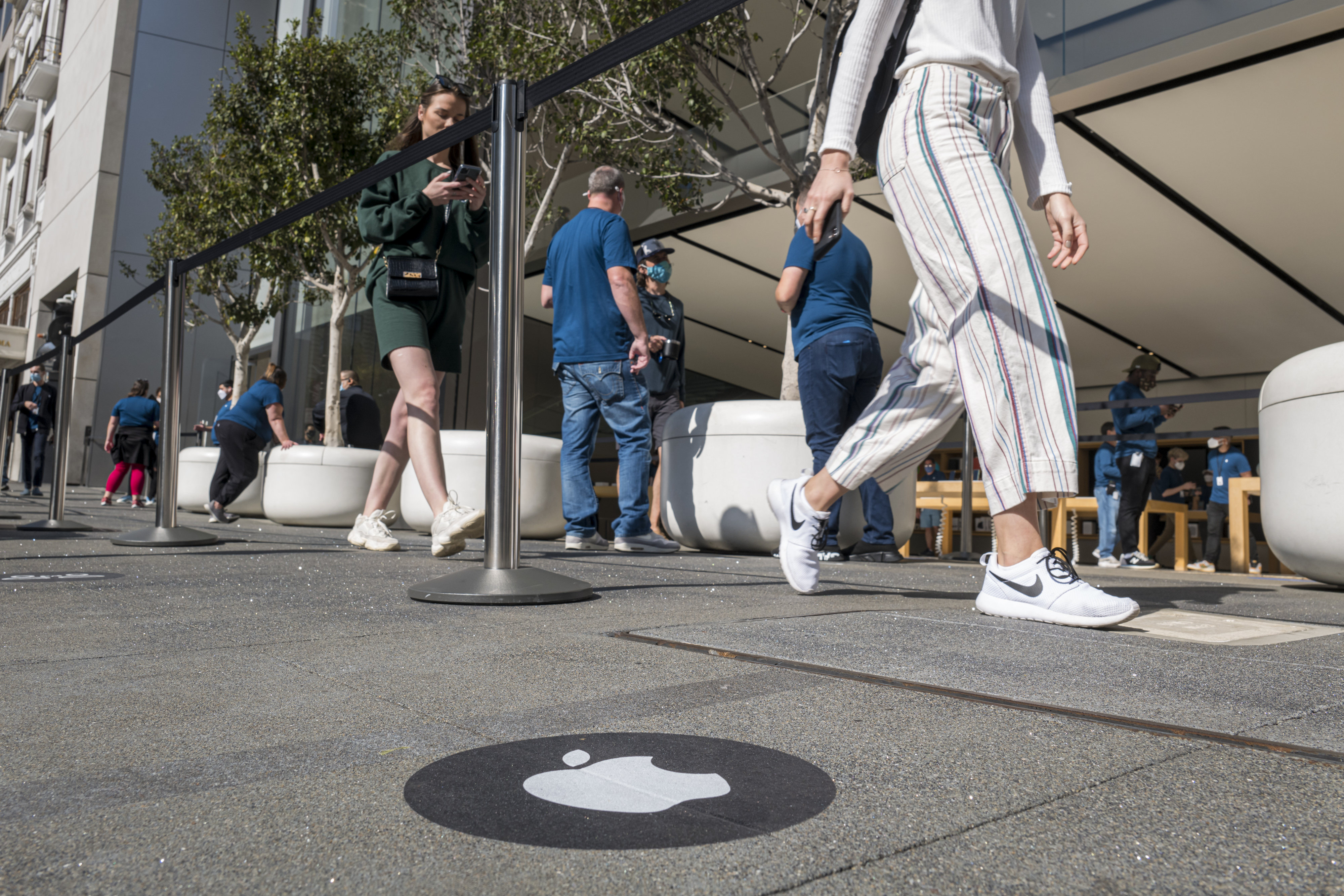 Pedestrians walk past an Apple Inc. store in San Francisco, California, U.S., on Friday, Oct. 23, 2020. The iPhone 12 and iPhone 12 Pro went on sale in stores, but with individual shopping sessions replacing the famous lines and crowds around locations.
