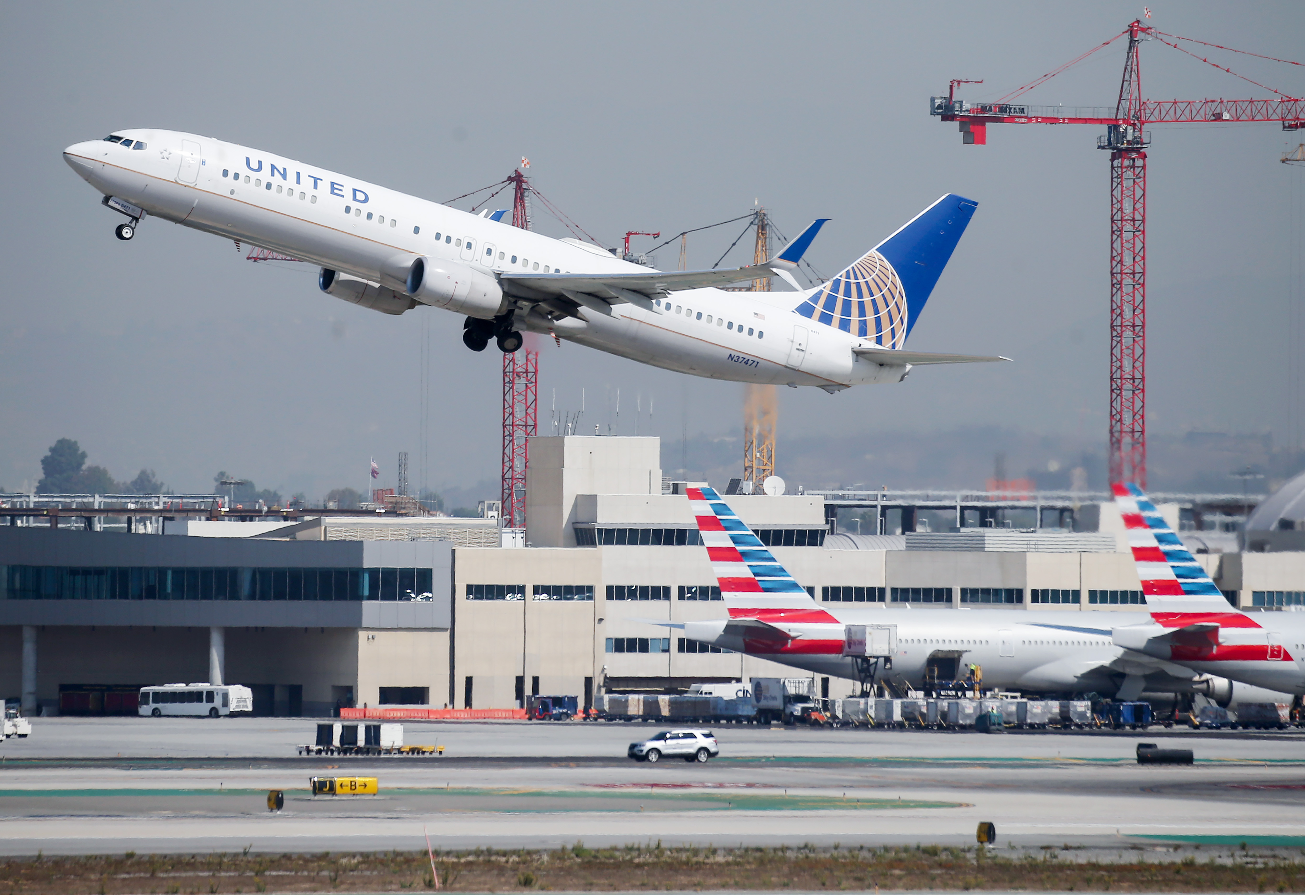 LOS ANGELES, CALIFORNIA - OCTOBER 01: A United Airlines plane takes off above American Airlines planes on the tarmac at Los Angeles International Airport (LAX) on October 1, 2020 in Los Angeles, California. United Airlines and American Airlines are set to start furloughing 32,000 employees today after negotiations for a new coronavirus aid package failed in Washington.  (Photo by Mario Tama/Getty Images)
