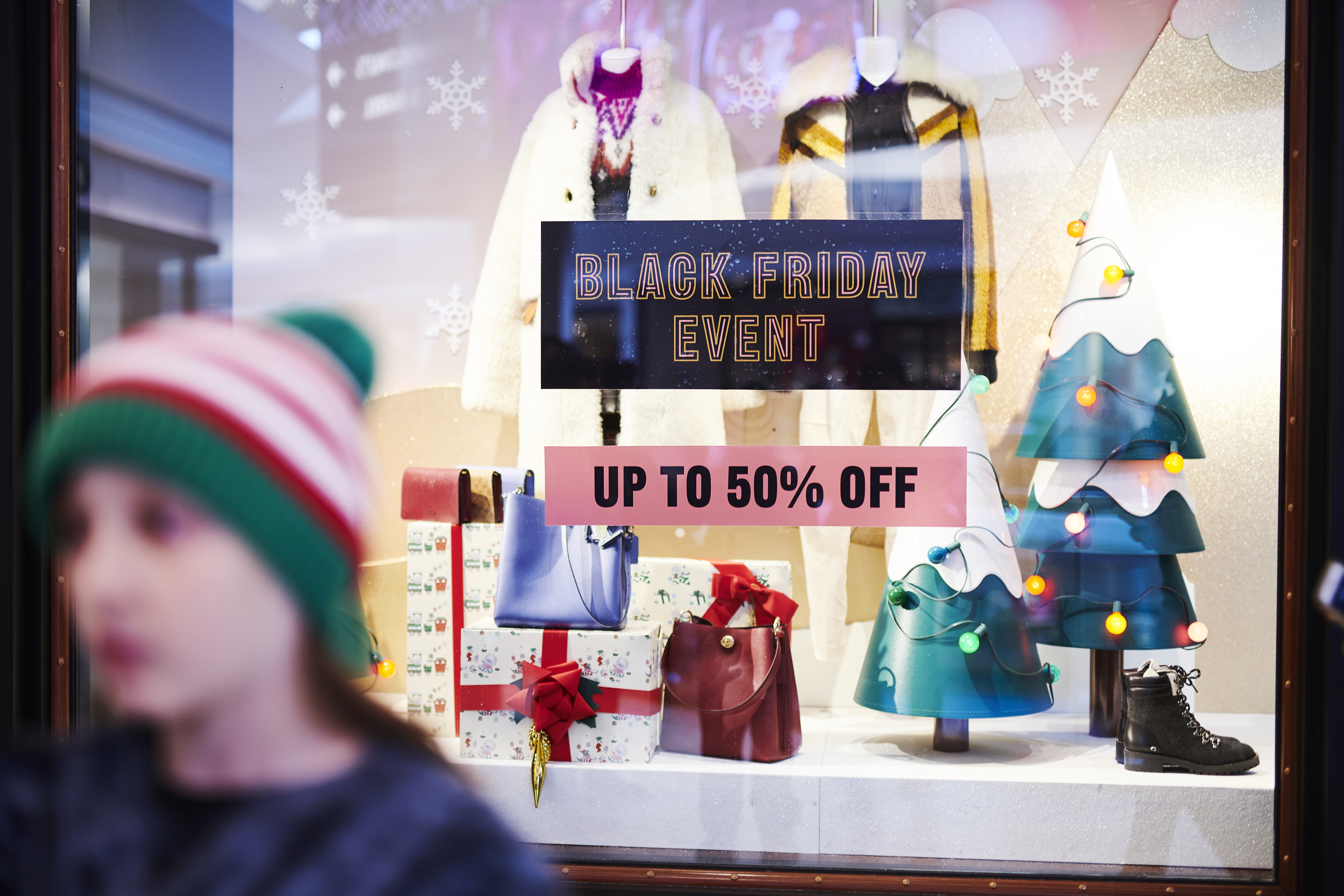 Shoppers walk past an advertisement for Black Friday sales displayed outside a store at The Mall at Short Hills shopping center on Black Friday in Short Hills, New Jersey on Nov. 29, 2019.