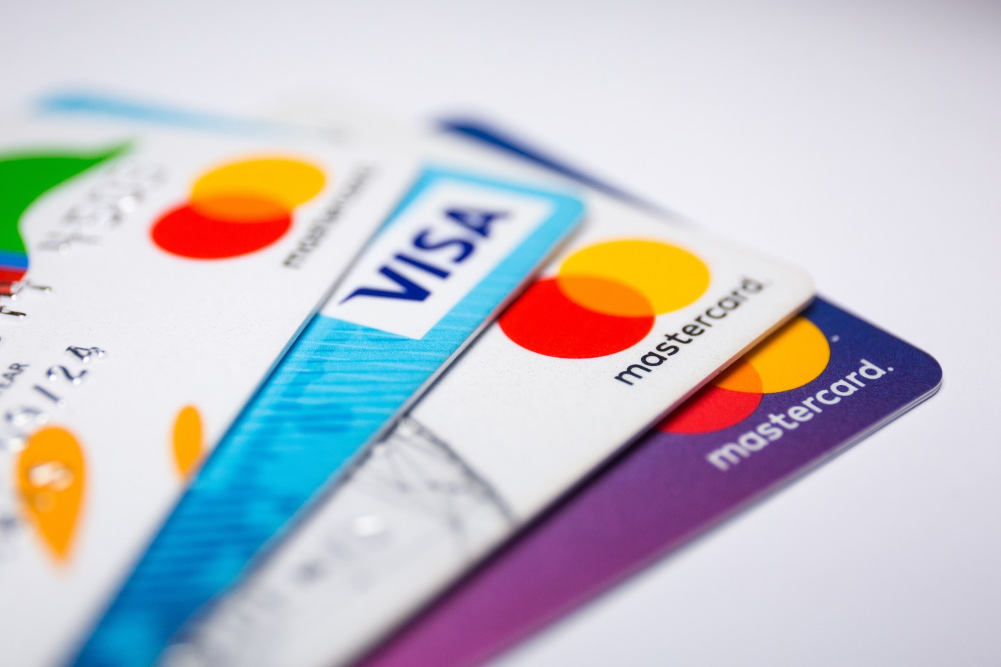 Four credit cards lay fanned out on a white surface