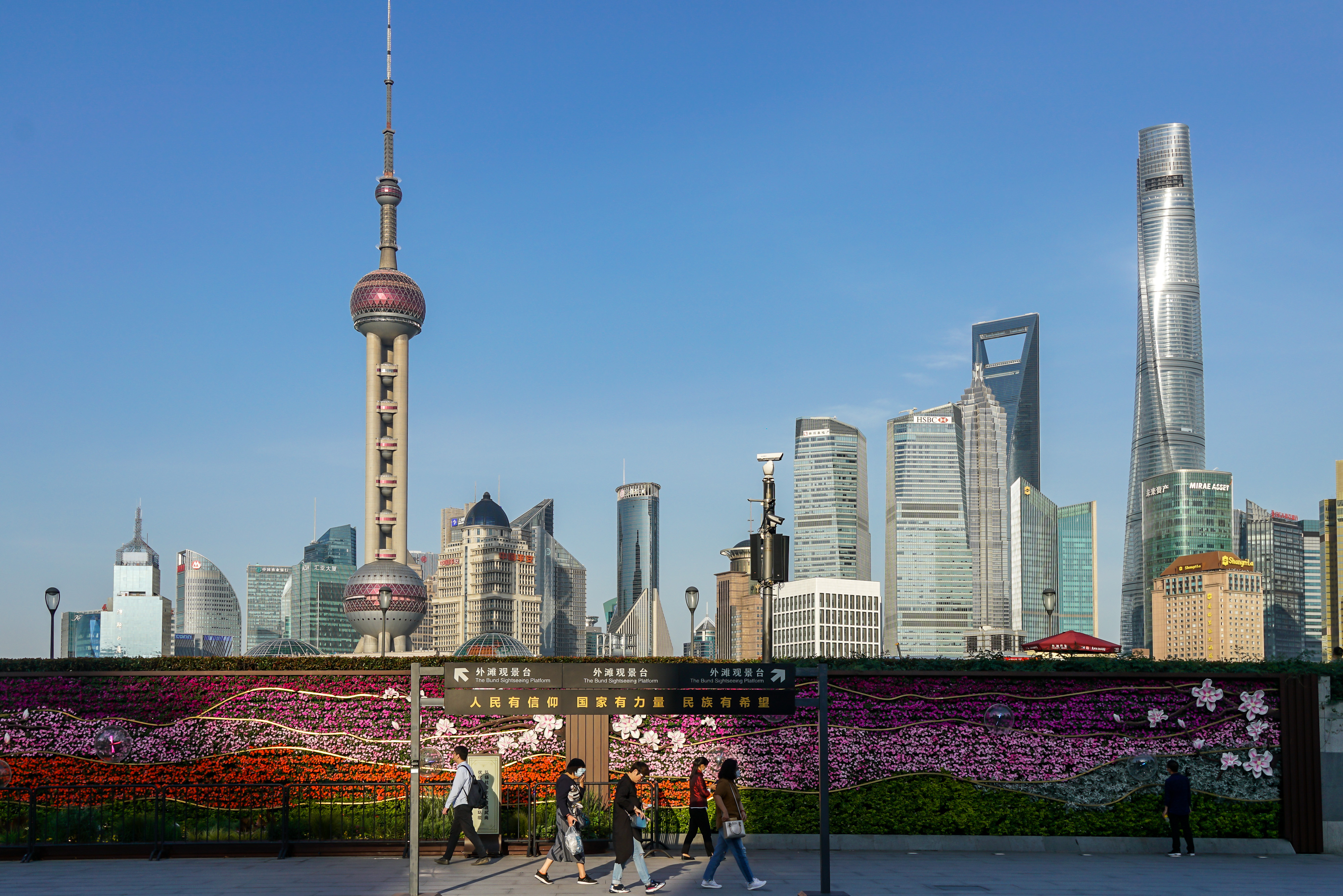 People wearing face masks walk at the Bund with a view of the skyline of the special economic zone Pudong with its skyscrapers on May 12, 2020 in Shanghai, China.