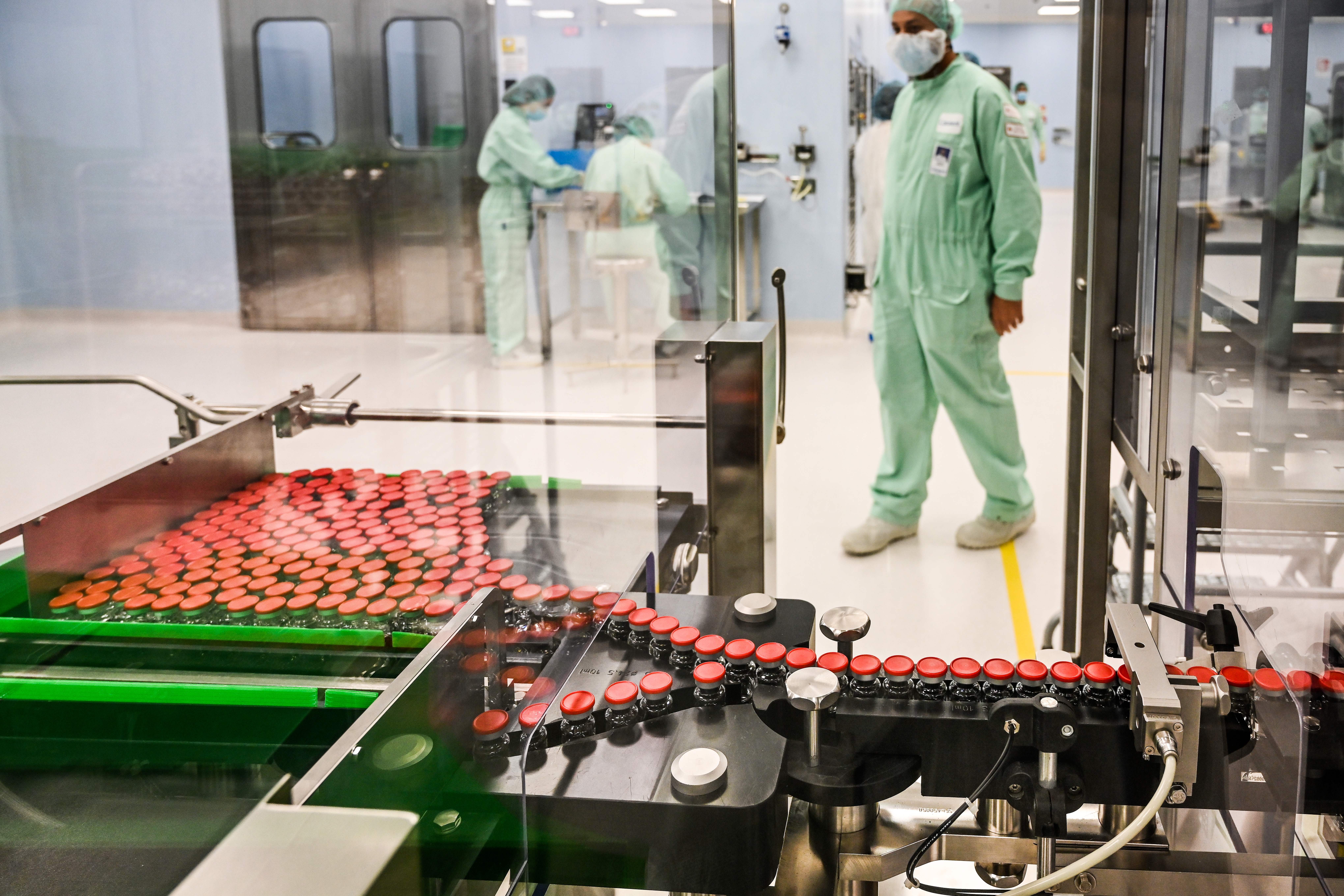 A laboratory technician supervises capped vials during filling and packaging tests for the large-scale production and supply of the University of Oxfords COVID-19 vaccine candidate.