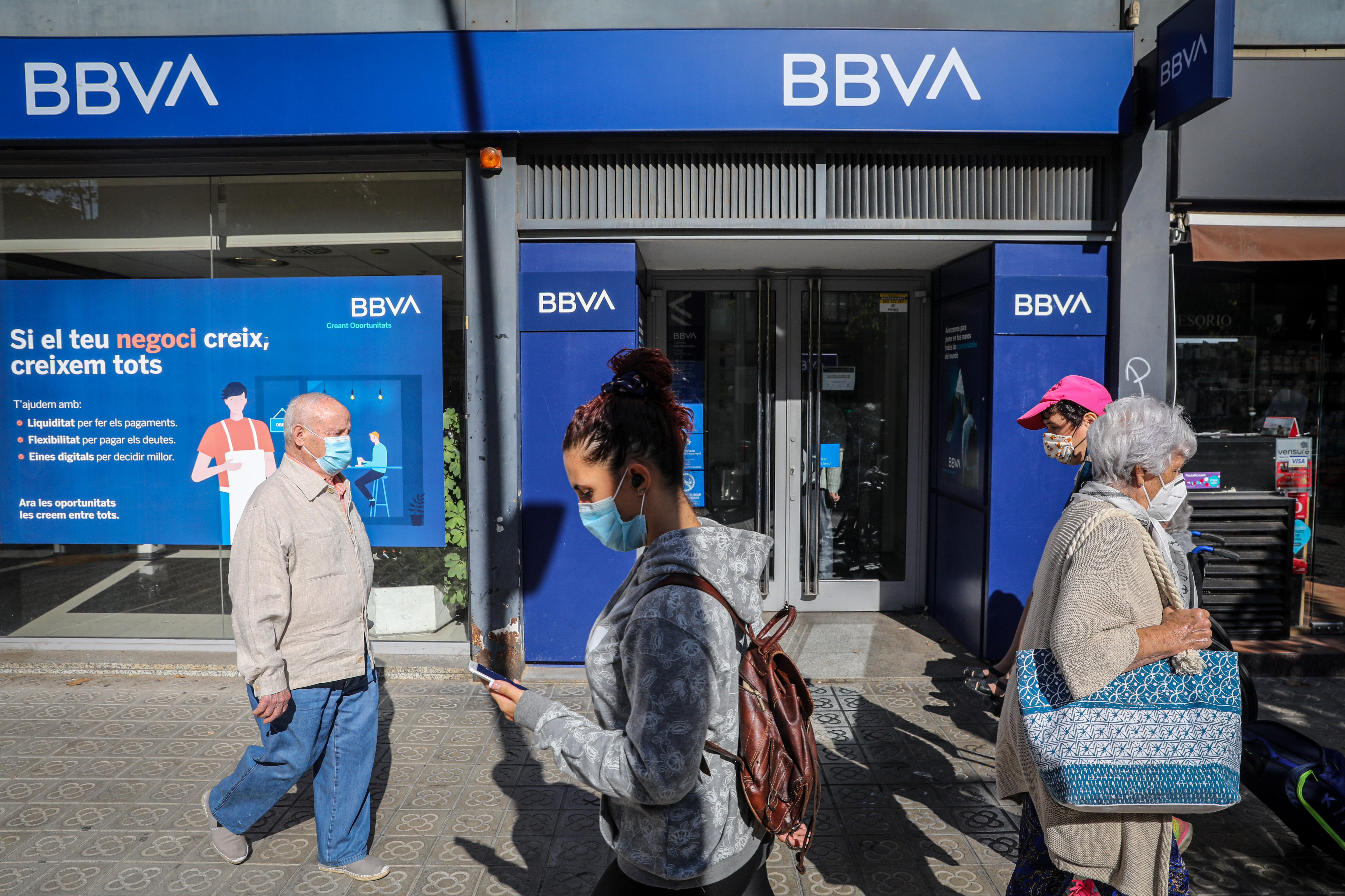Pedestrians wearing protective face masks pass a branch of Banco Bilbao Vizcaya Argentaria SA (BBVA) in Barcelona, Spain on Tuesday, Oct. 6, 2020. Banco de Sabadell SA has been in contact with BBVA and Kutxabank SA to explore a potential tie-up in recent weeks, El Confidencial reports, citing unidentified people familiar with the matter. Photographer: Angel Garcia/Bloomberg via Getty Images