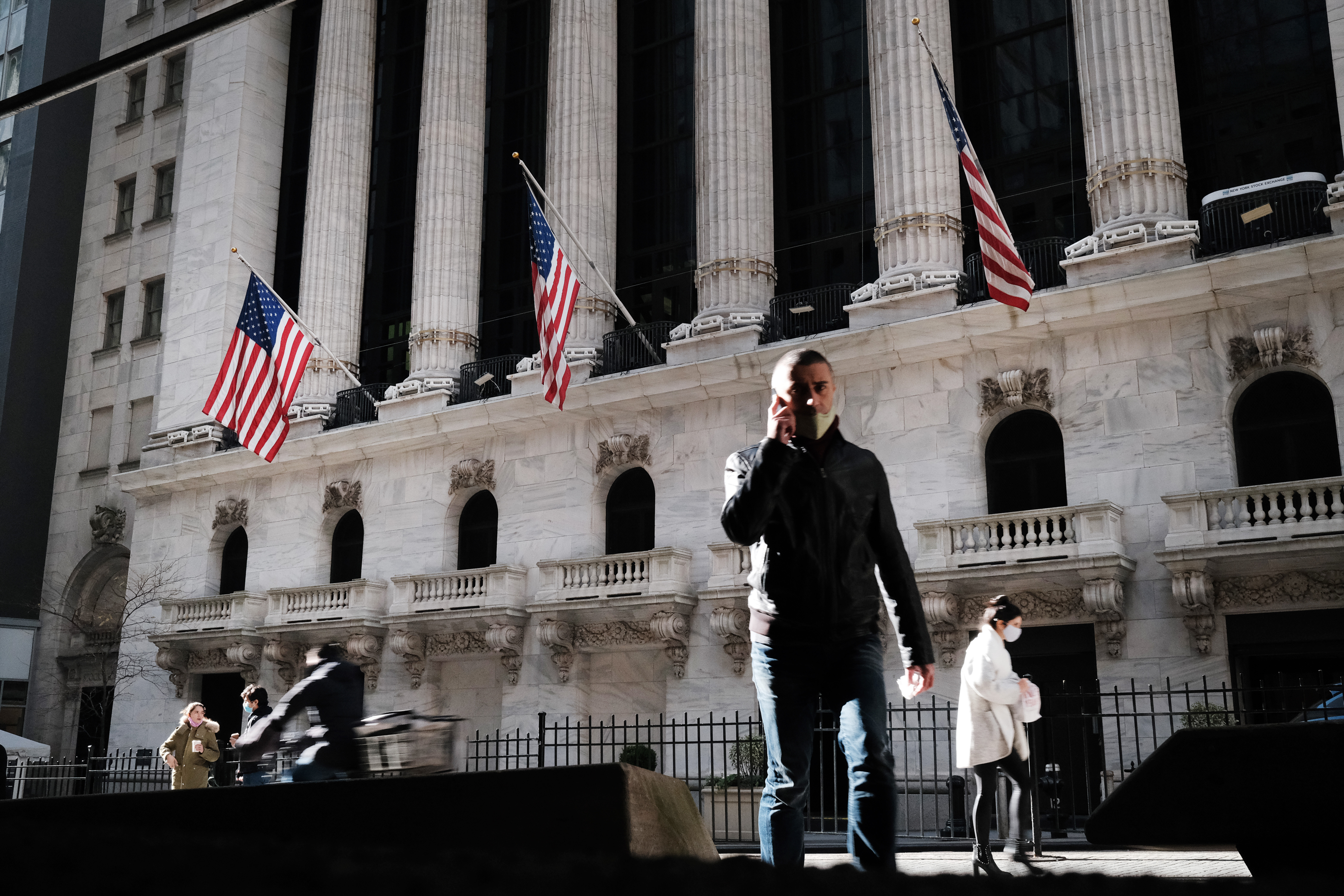 People walk past the New York Stock Exchange (NYSE) on November 24, 2020 in New York City. As investor's fear of an election crisis eases, the DowJones Industrial Average passed the 30,000 milestone for the first time on Tuesday morning.