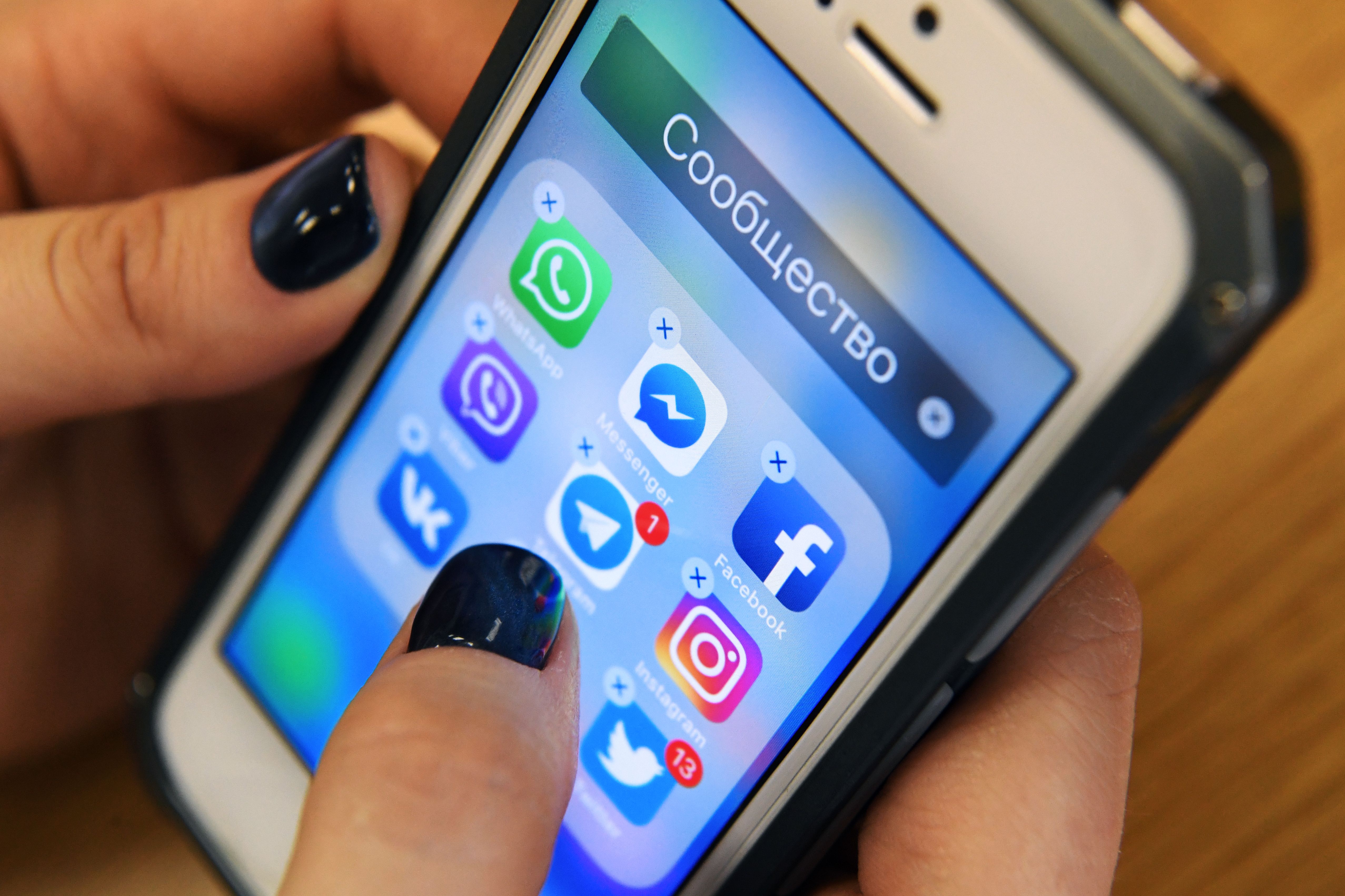 A woman holds a smart phone with the icons for the social networking apps Facebook, Instagram, Twitter and others seen on the screen in Moscow on March 23, 2018.