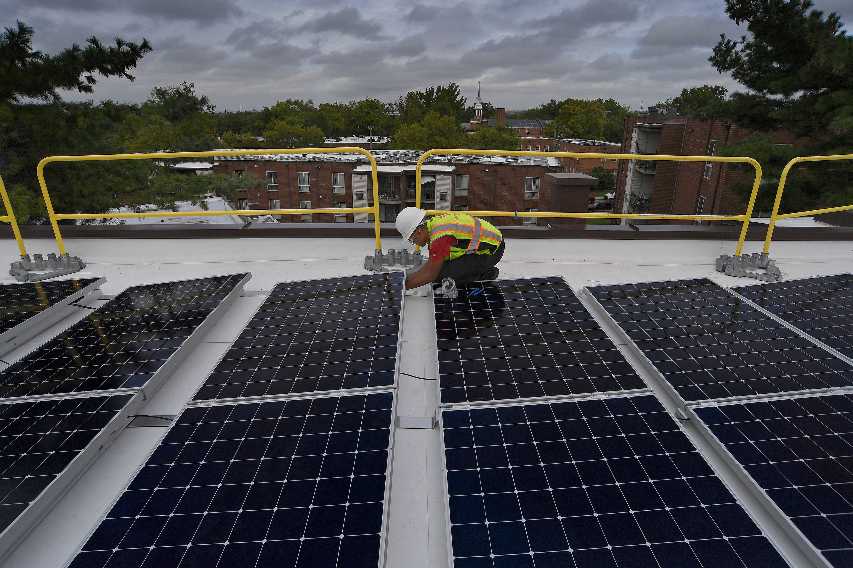 A trainee installing solar panels on the roof of an apartment complex in SE Washington D.C, August 2019.