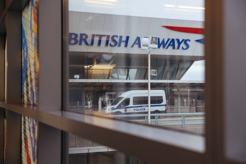 A police van sits outside the British Airways terminal at John F. Kennedy International Airport (JFK) in New York, U.S., on Thursday, Dec. 24, 2020.  New York Mayor Bill de Blasio said the city will strictly enforce quarantine rules for all travelers arriving in the city during the holidays, particularly those from the U.K., where a highly contagious new COVID-19 strain has been detected.