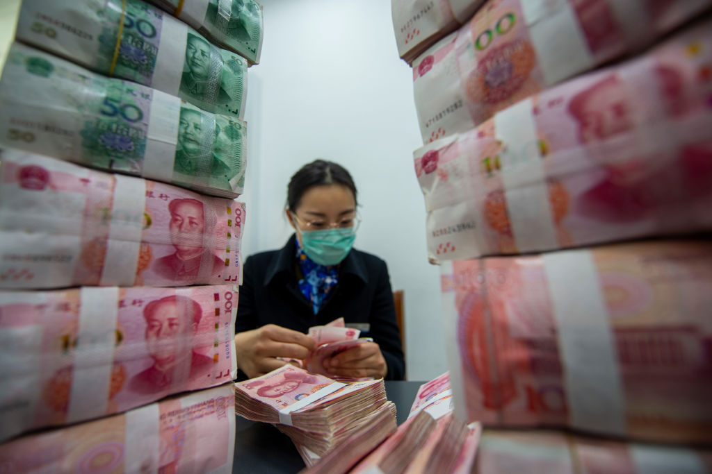 A worker counts banknotes at a bank outlet in Hai'an in east China's Jiangsu province on April 4, 2020.