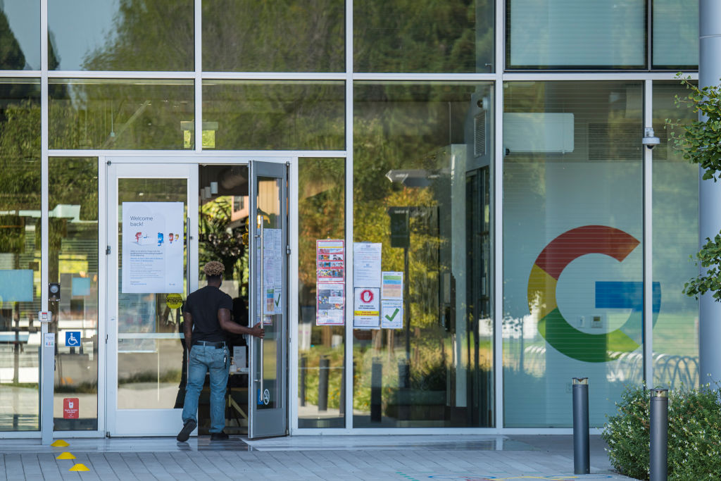 A person walks into a building at the Google campus in Mountain View, California, U.S., on Monday, July 27, 2020. Alphabet Inc.'s Google will let employees work from home until July 2021, once again pushing back the re-opening of its offices as the coronavirus continues to rage in many parts of the U.S.