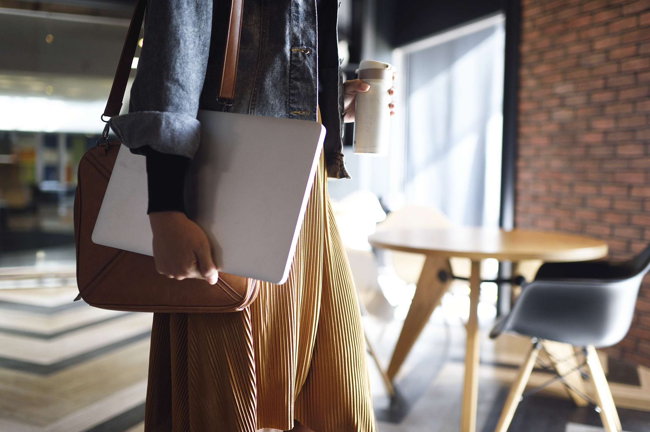 Woman carrying laptop, purse and reusable coffee cup to work