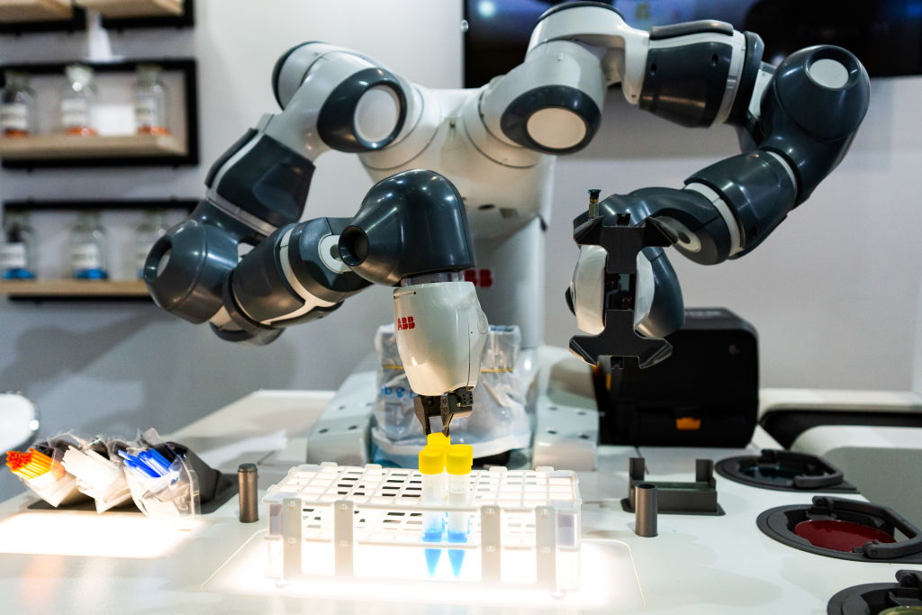 An industrial robot manipulating test tubes of liquid.