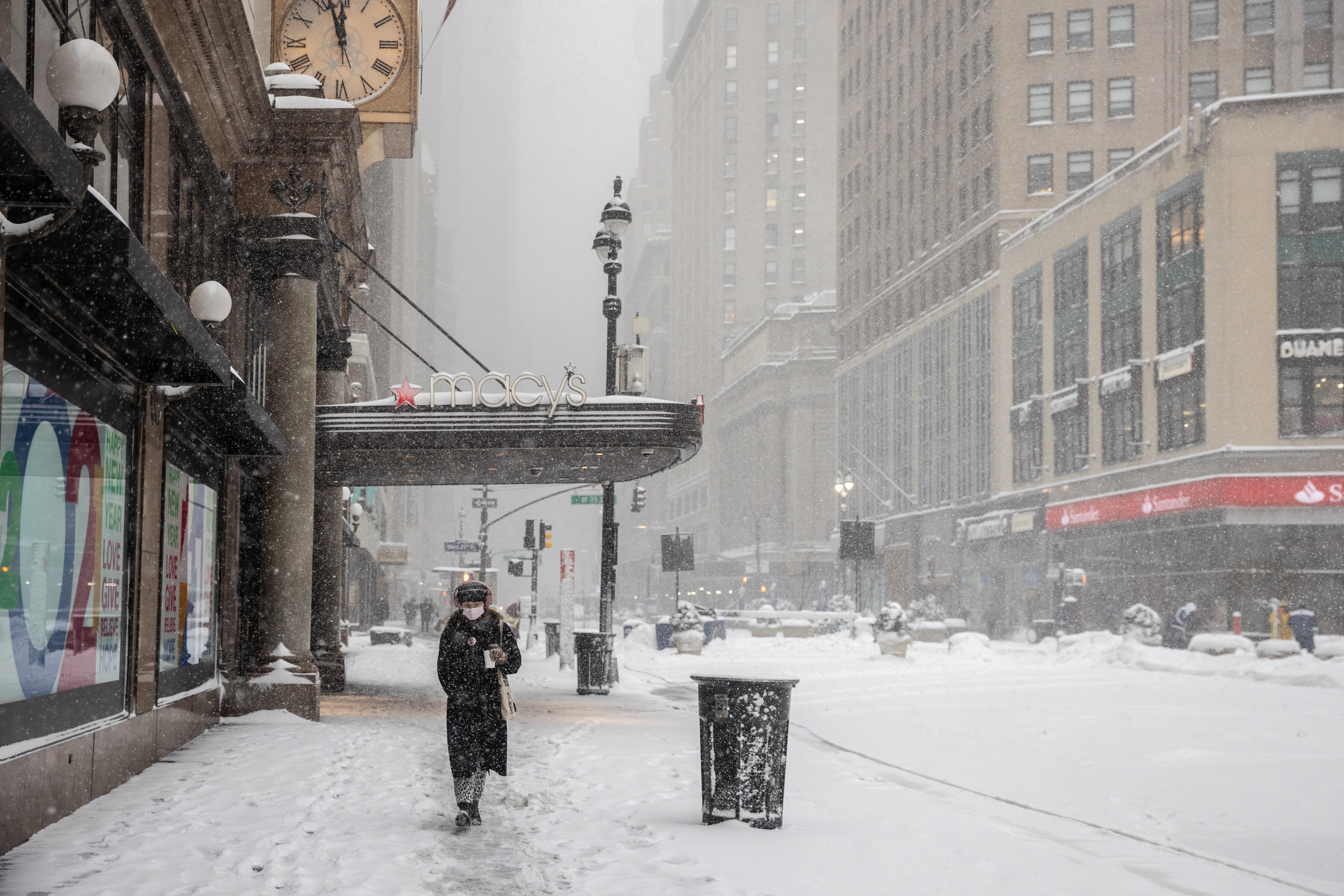 A pedestrian passes in front of Macy's flagship department store as snow falls in the Herald Square area of New York City on Feb. 1, 2021.