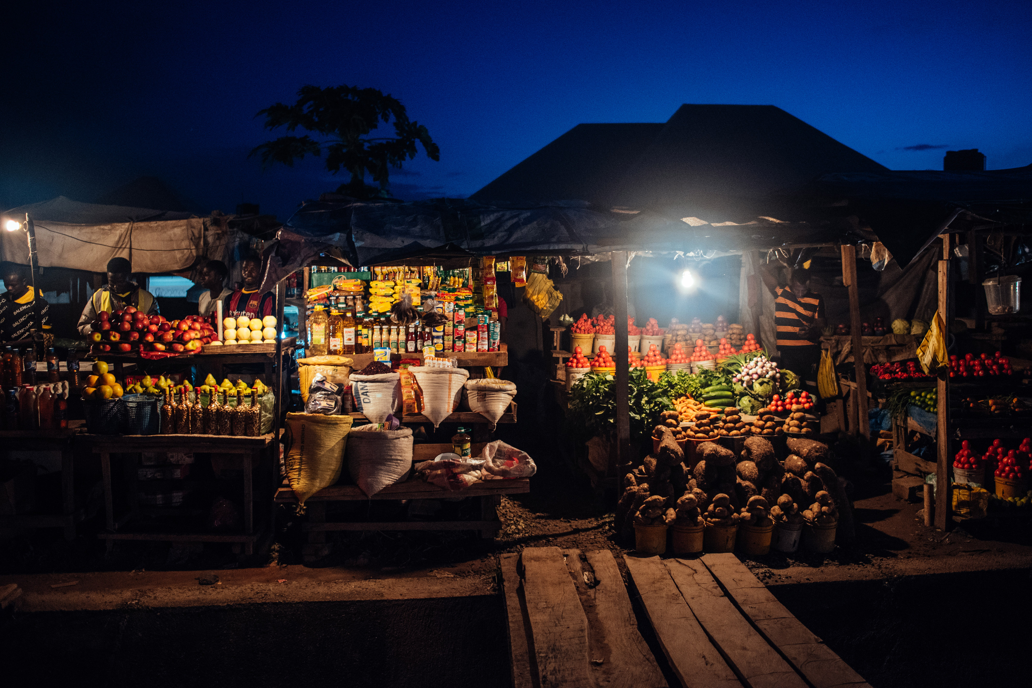Vendors sell fresh produce on stalls at a fruit market as day breaks in the Lugbe district of Abuja, Nigeria, on Tuesday, Sept. 1, 2020. By the end of the year, as many as 12,000 people globally could die a day from hunger linked to Covid-19, potentially more than those perishing from the virus itself, charity Oxfam International estimates.