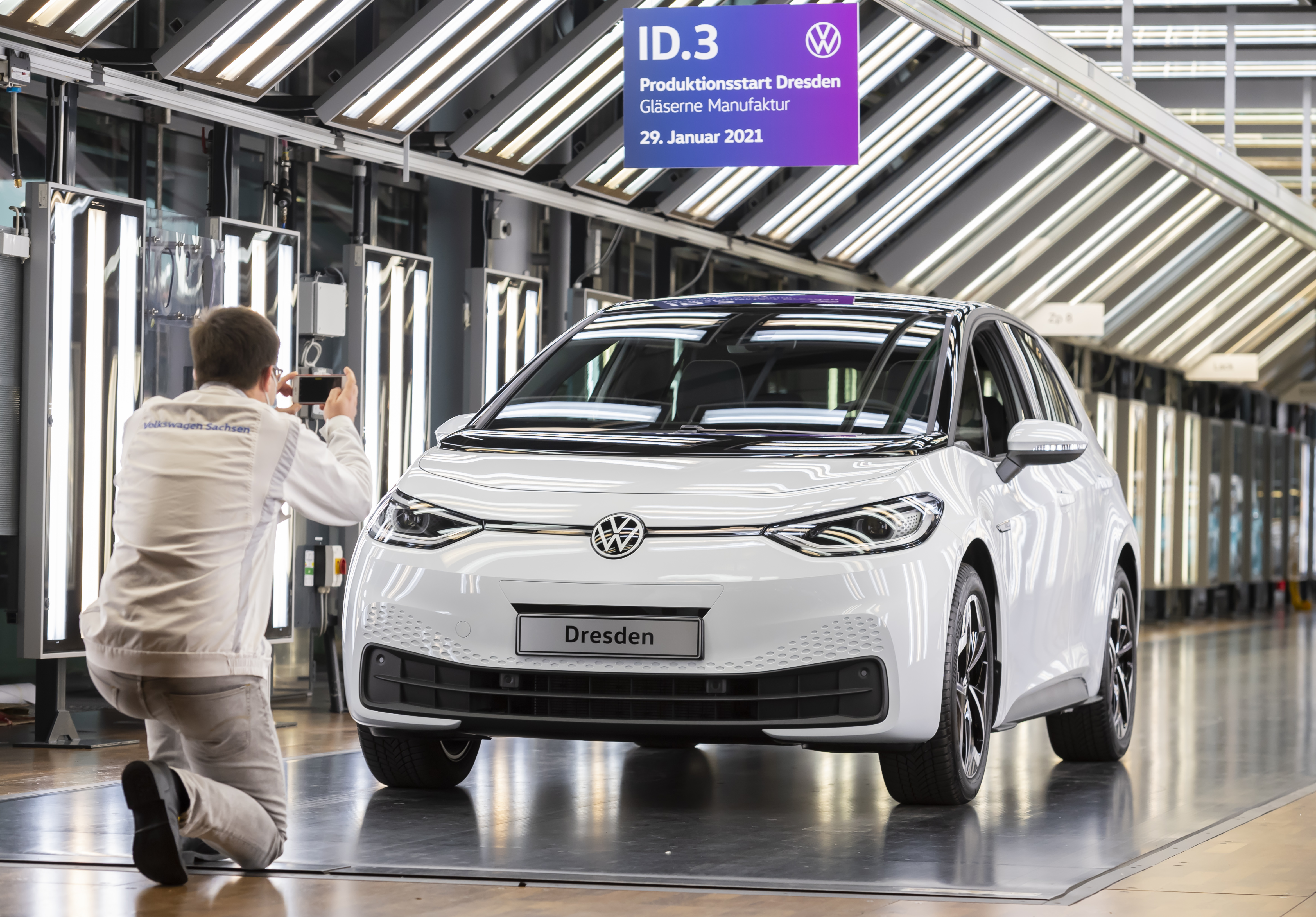 A VW worker takes a photo of an ID.3 in the light tunnel. Production of the electric model has officially begun at Volkswagen's Transparent Factory.