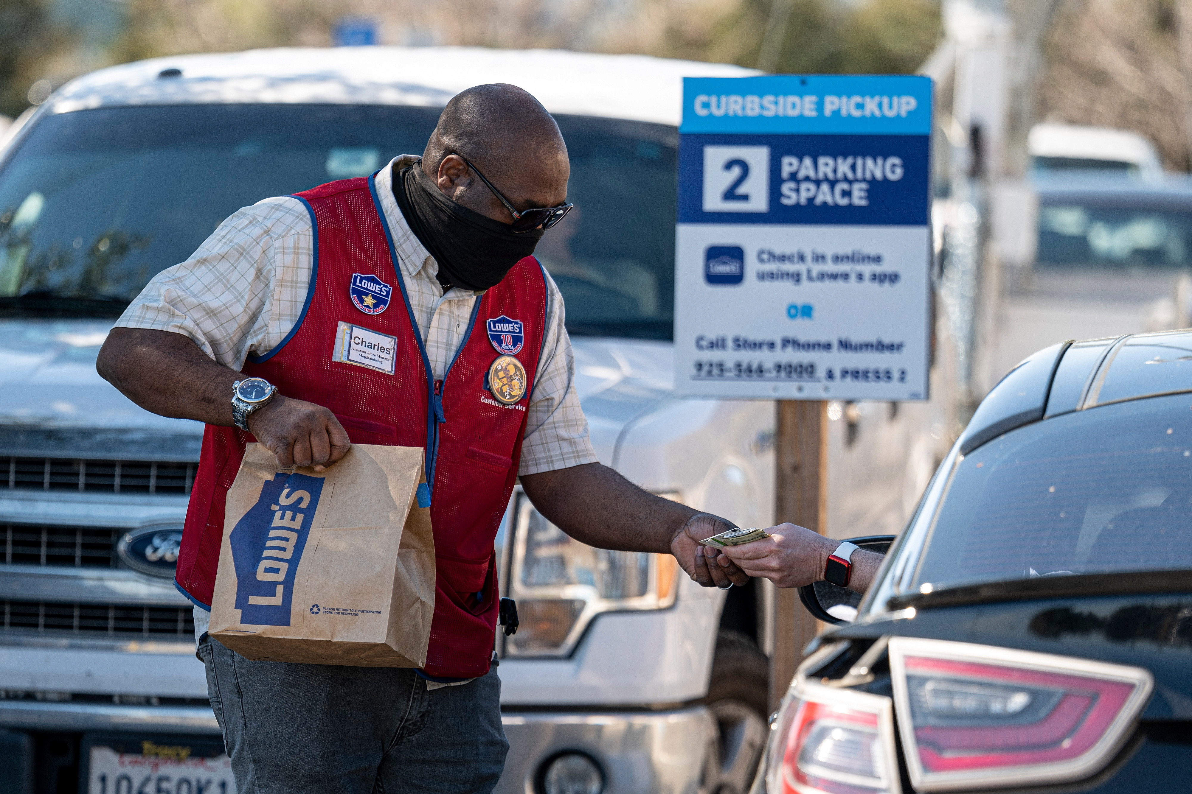A worker wearing a protective mask delivers a purchase to a customer at the curbside pickup area of a Lowe’s store in Concord, Calif., on Feb. 23, 2021.
