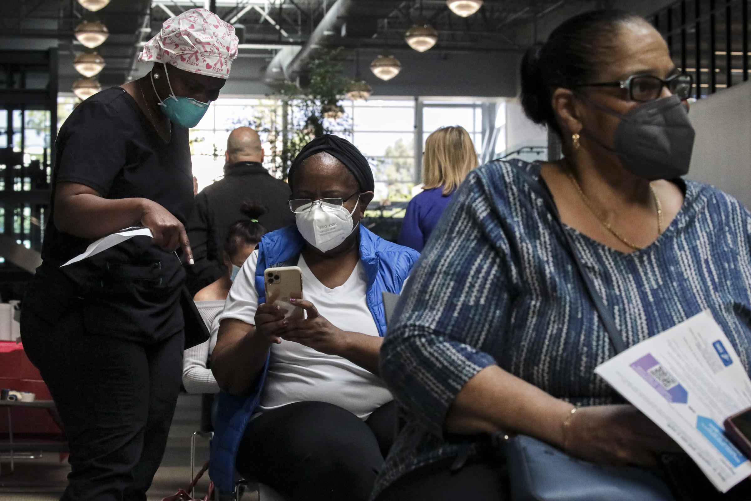 Nurse Fabienne Jean Julien (left) helps a client secure a second dose appointment while in line at a super vaccination site in Rancho Cucamonga, Calif. Online registration systems have been convenient for many vaccine seekers—but a significant barrier for many others.