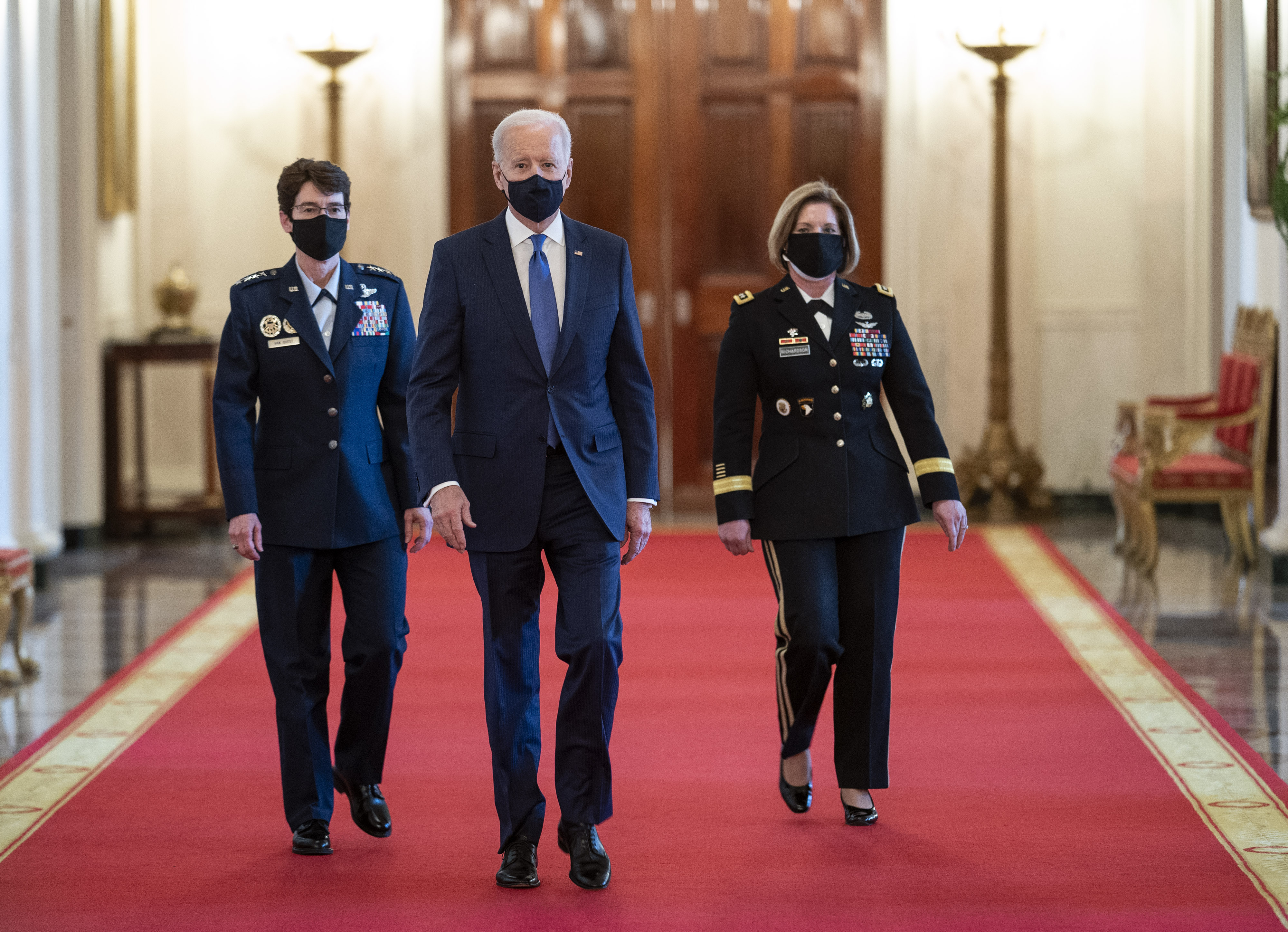 U.S. President Joe Biden, center, arrives with General Jacqueline Van Ovost, commander of the U.S. Transportation Command nominee for U.S. President Joe Biden, left, and Lieutenant General Laura Richardson, commander of the U.S. Southern Command nominee for U.S. President Joe Biden, during an event in the State Dining Room of the White House in Washington, D.C., U.S., on Monday, March 8, 2021. Biden vowed an 'all hands on deck effort' to combat sexual assault in the military during an International Women Day's event on Monday, where he appointed two women as four-star generals.