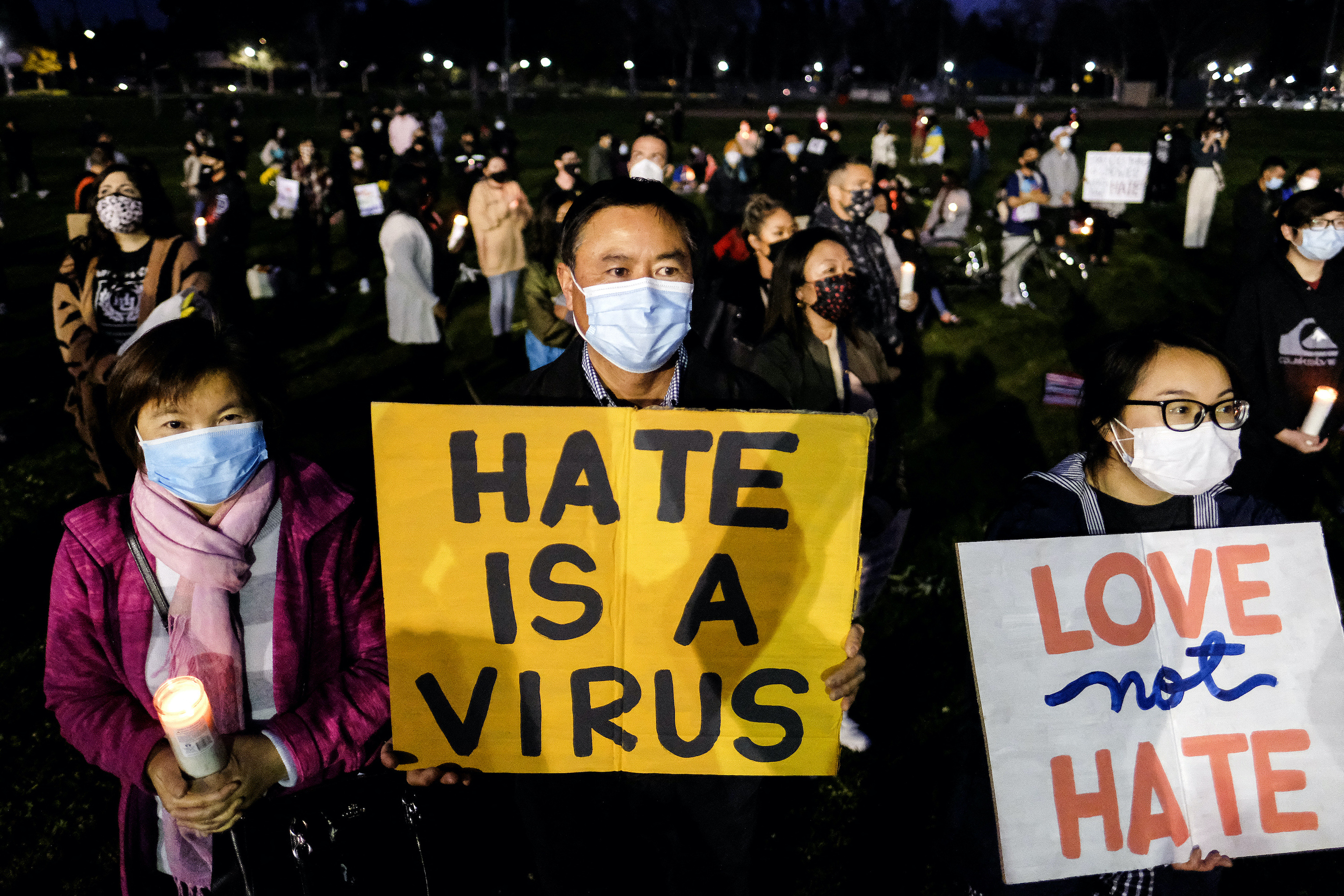 People holding candles and anti-hate signs take part in a candlelight vigil in standing up against Asian American Pacific Islander (AAPI) hate and violence, at Almansor Park in Alhambra, California, on March 20, 2021.