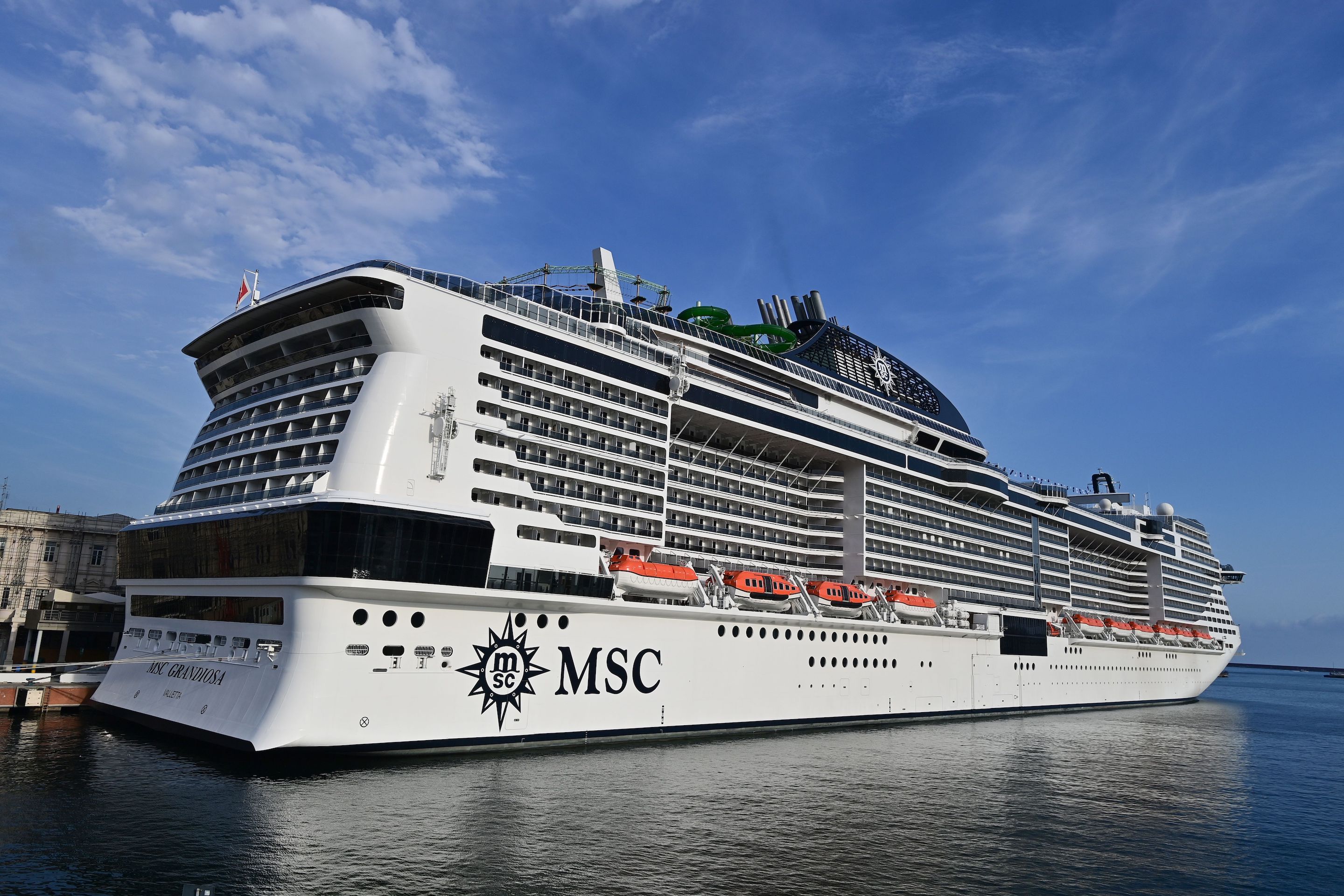 A picture taken in the northern Italian port of Genoa on August 16, 2020 shows the MSC Grandiosa cruise liner leaving the port pulled by a little boat after six-and-half months of inactivity due to the novel coronavirus, COVID-19, pandemic.