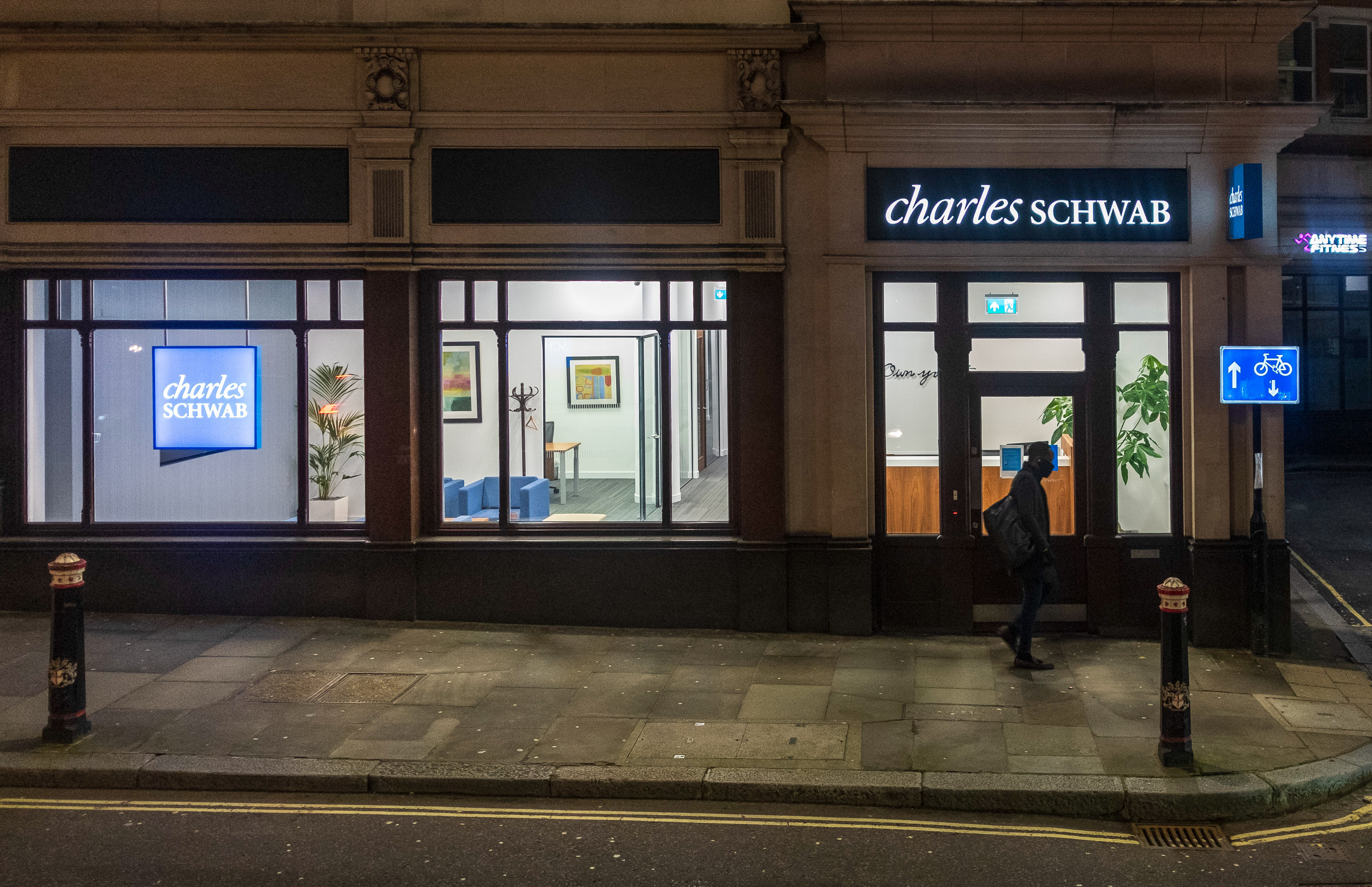 :A pedestrian walks past American multinational financial services company, Charles Schwab Corporation, in London.