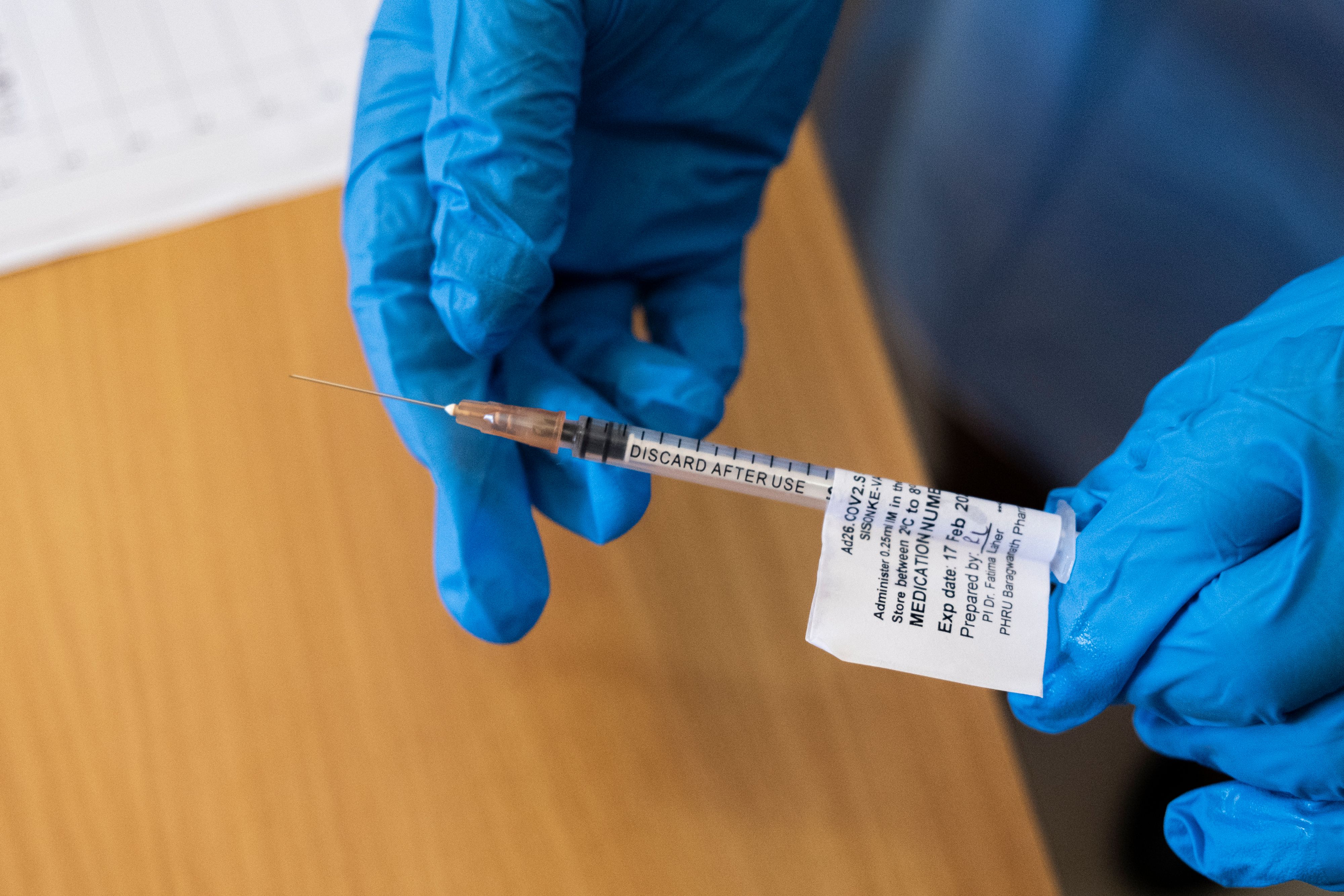 A health worker in Soweto, South Africa holds a dose of the Johnson & Johnson COVID-19 vaccine. U.S. health authorities today recommended a pause in administering the vaccine to examine rare blood clotting incidents, and nations including South Africa quickly followed suit.