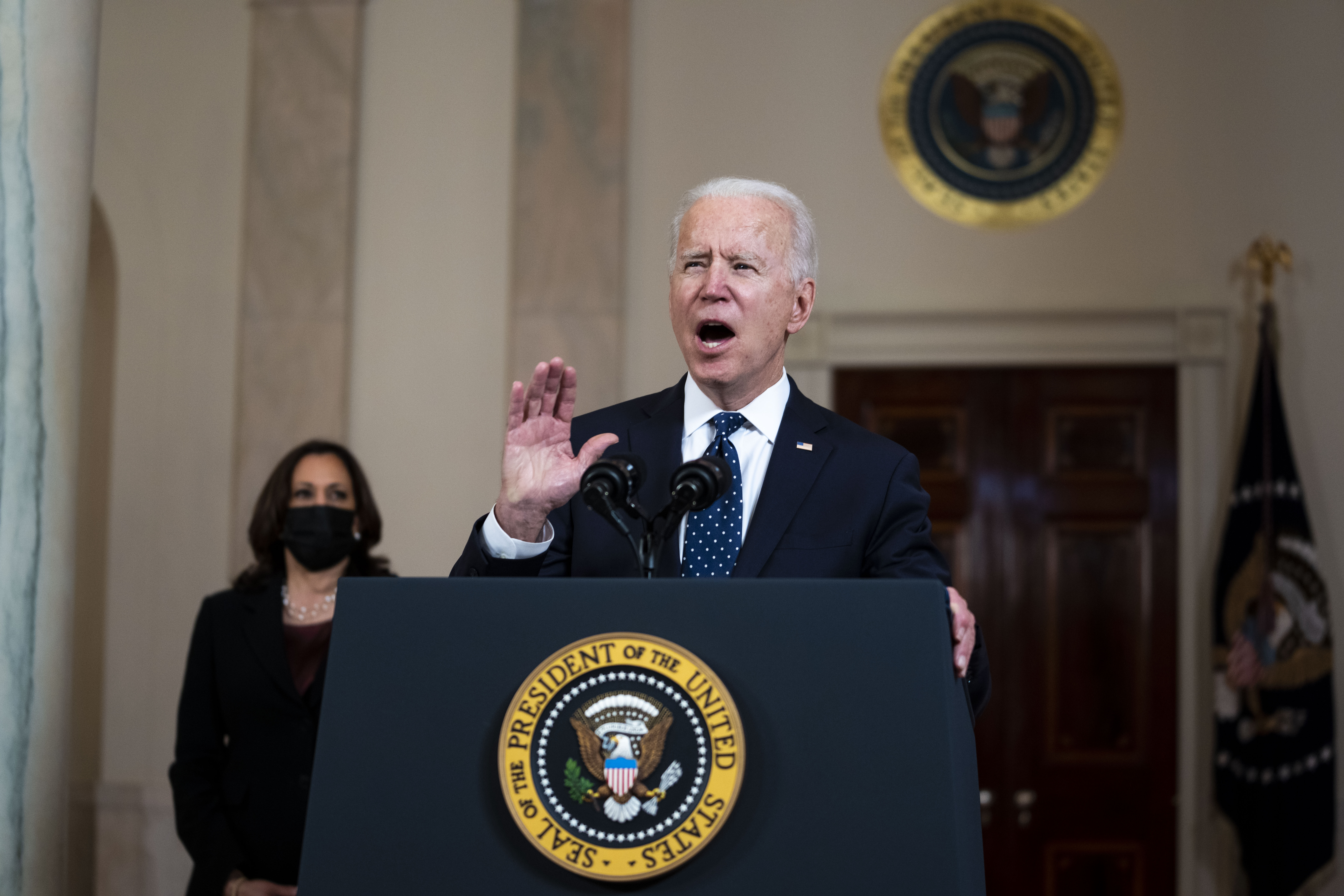 U.S. President Joe Biden speaks as Vice President Kamala Harris listens in the Cross Hall of the White House in Washington, D.C. on April 20, 2021.