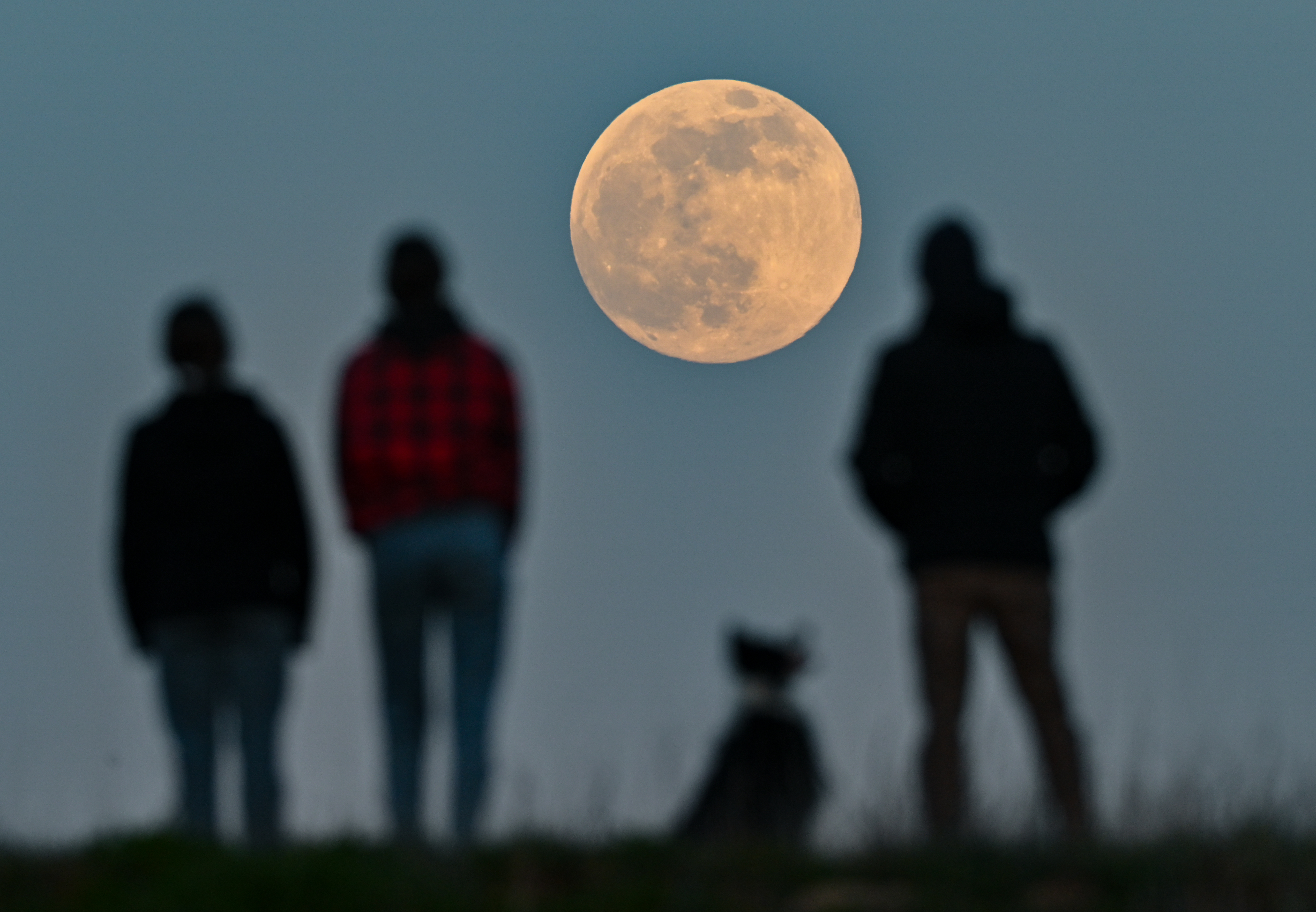 People stand on a hill and watch the rising moon. The waxing moon is 99.7% visible that evening. On April 27, 2021, a so-called supermoon occurs. Then the distance between the moon and Earth is smaller than usual.