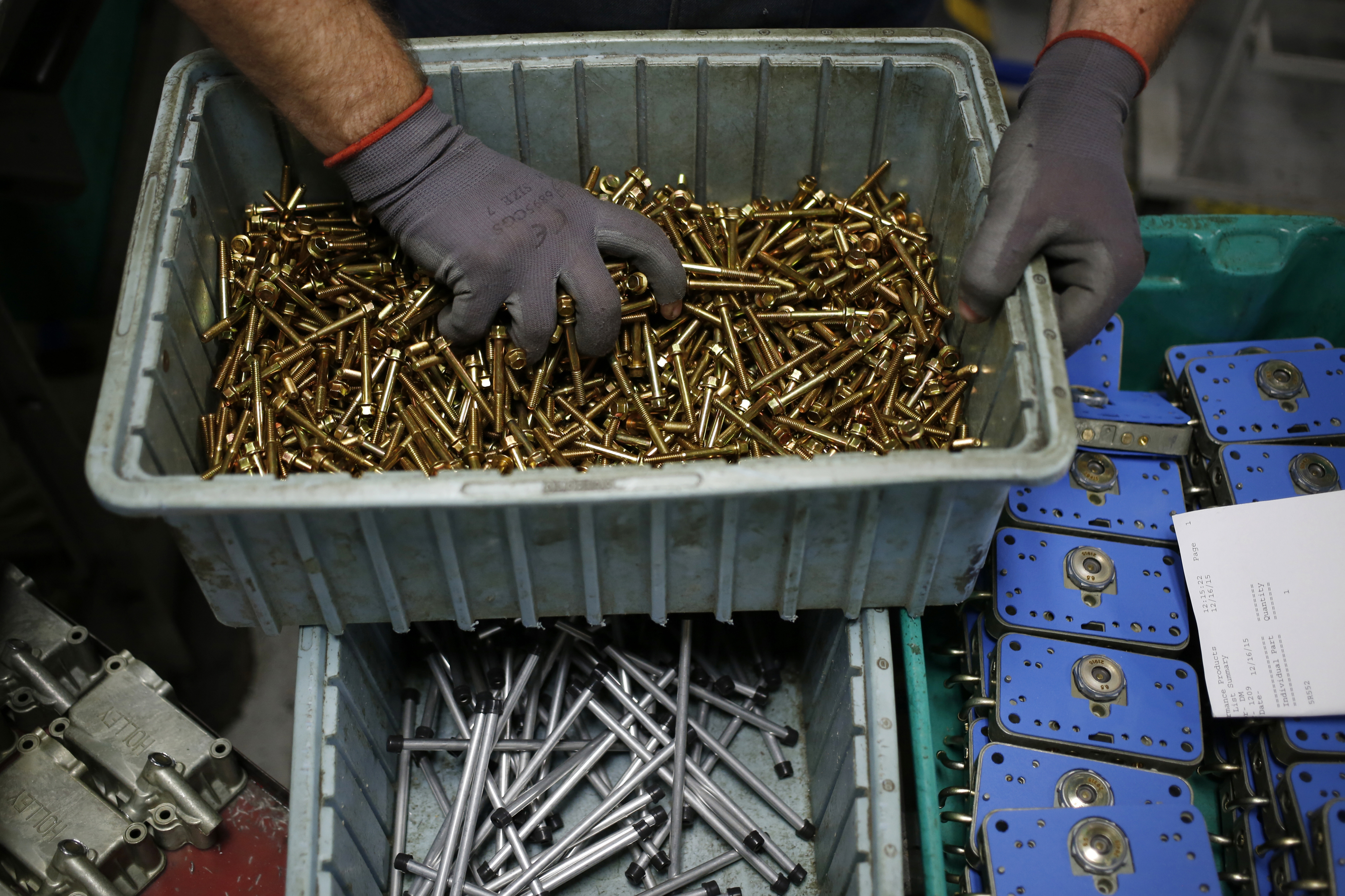 A worker grabs a handful of carburetor components on an assembly line at the Holley Performance Products Inc. manufacturing facility in Bowling Green, Kentucky.