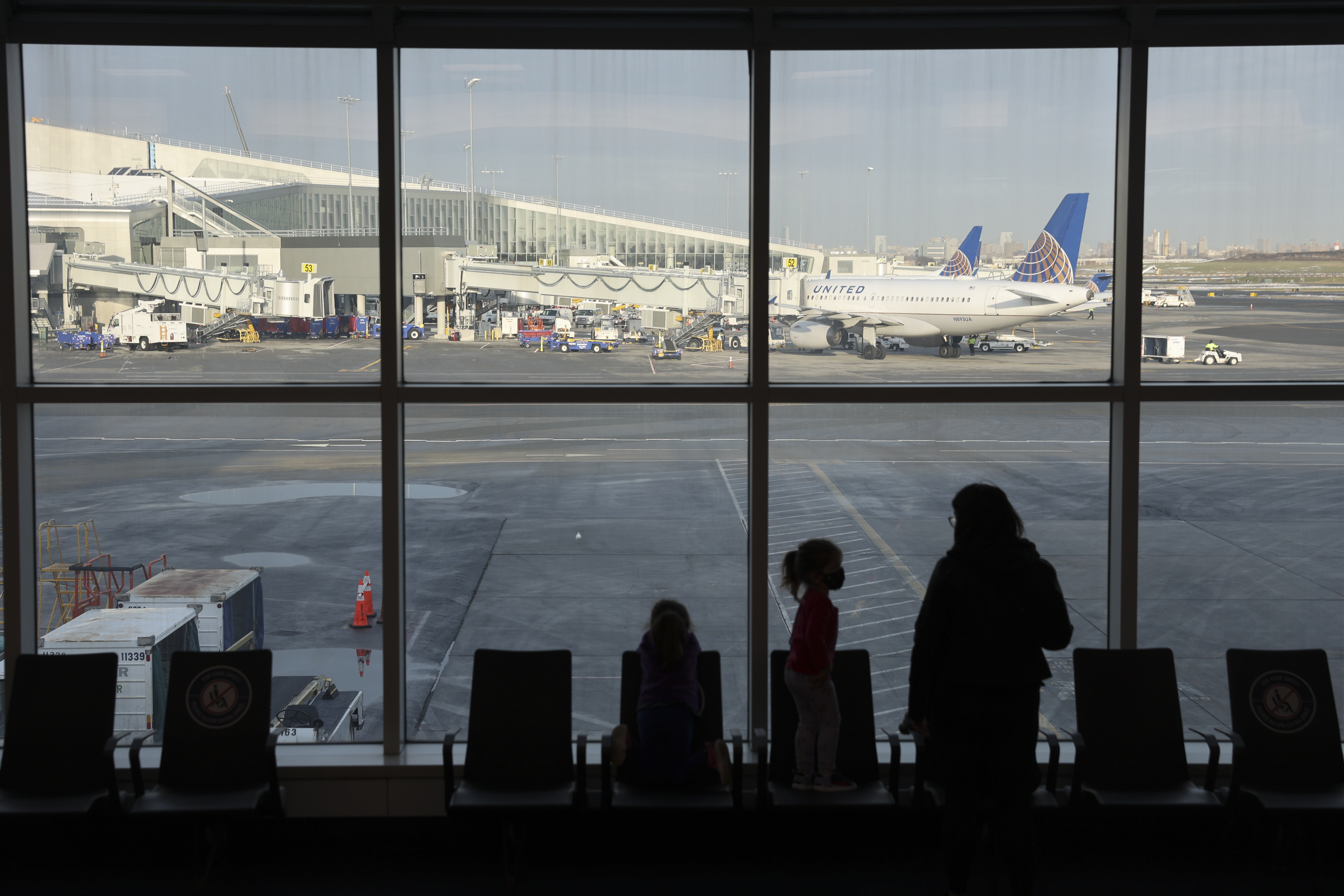 Travelers look out a window at LaGuardia Airport (LGA) in New York, U.S., on Thursday, Dec. 24, 2020