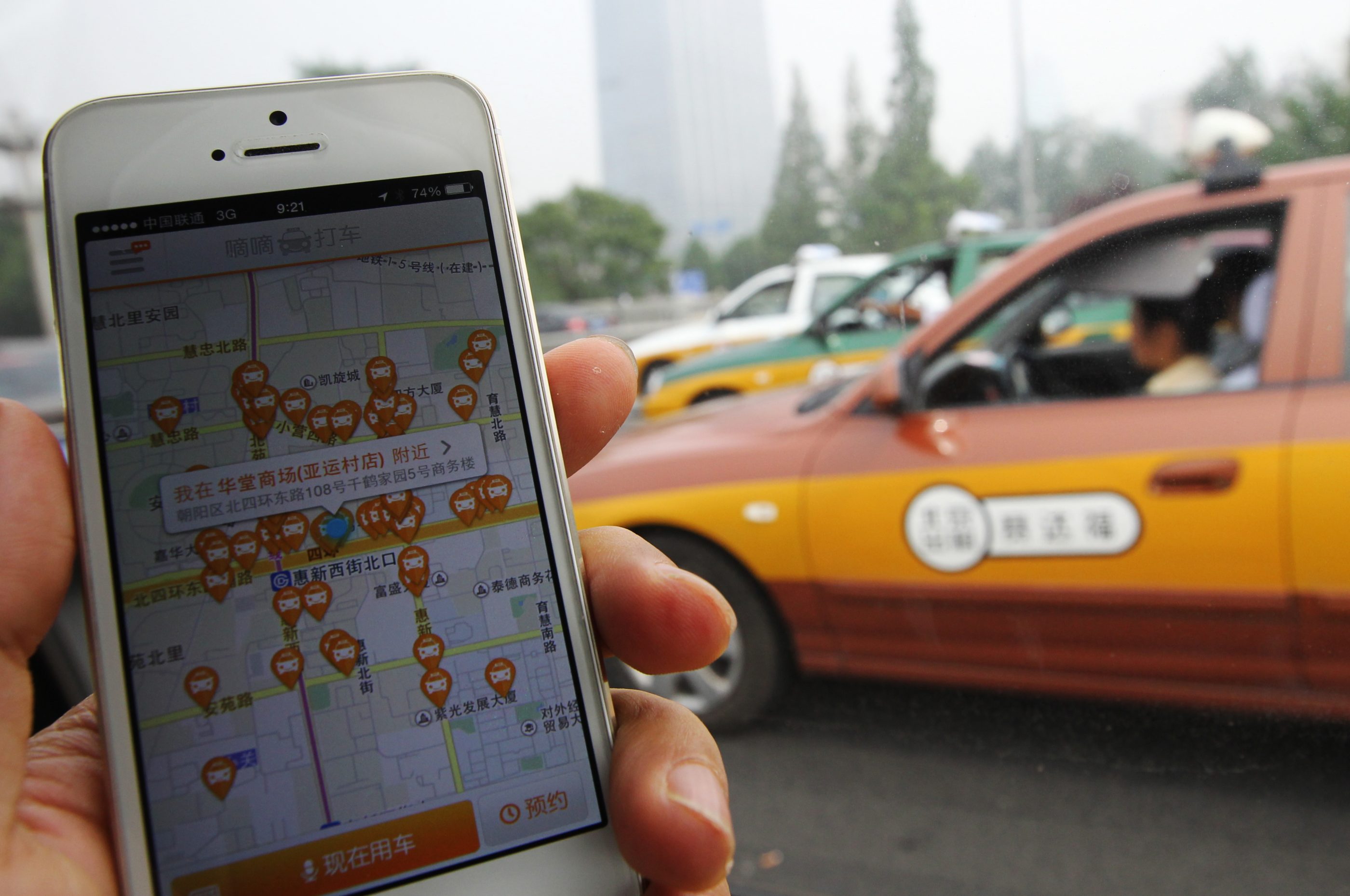 The screen of a mobile phone shows the Didi Dache app while a taxi passes by in Beijing, China. Didi Dache has become China's most popular mobile app to call for a taxi ride.