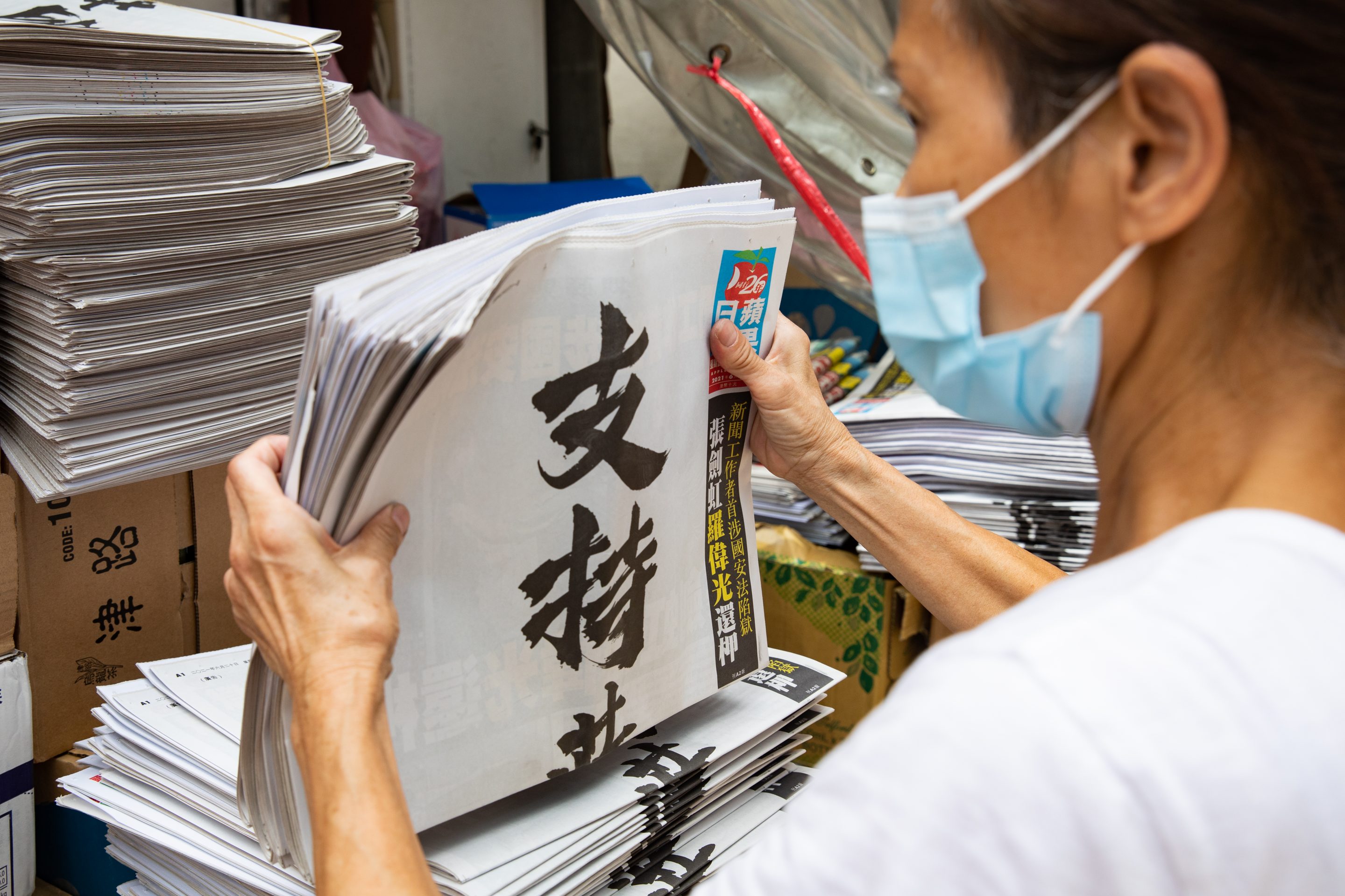 A newsstand vendor arranges copies of Next Digital’s Apple Daily, with a front page advertisement voicing support for the newspaper on its 26th anniversary, on June 20, 2021, in Hong Kong.