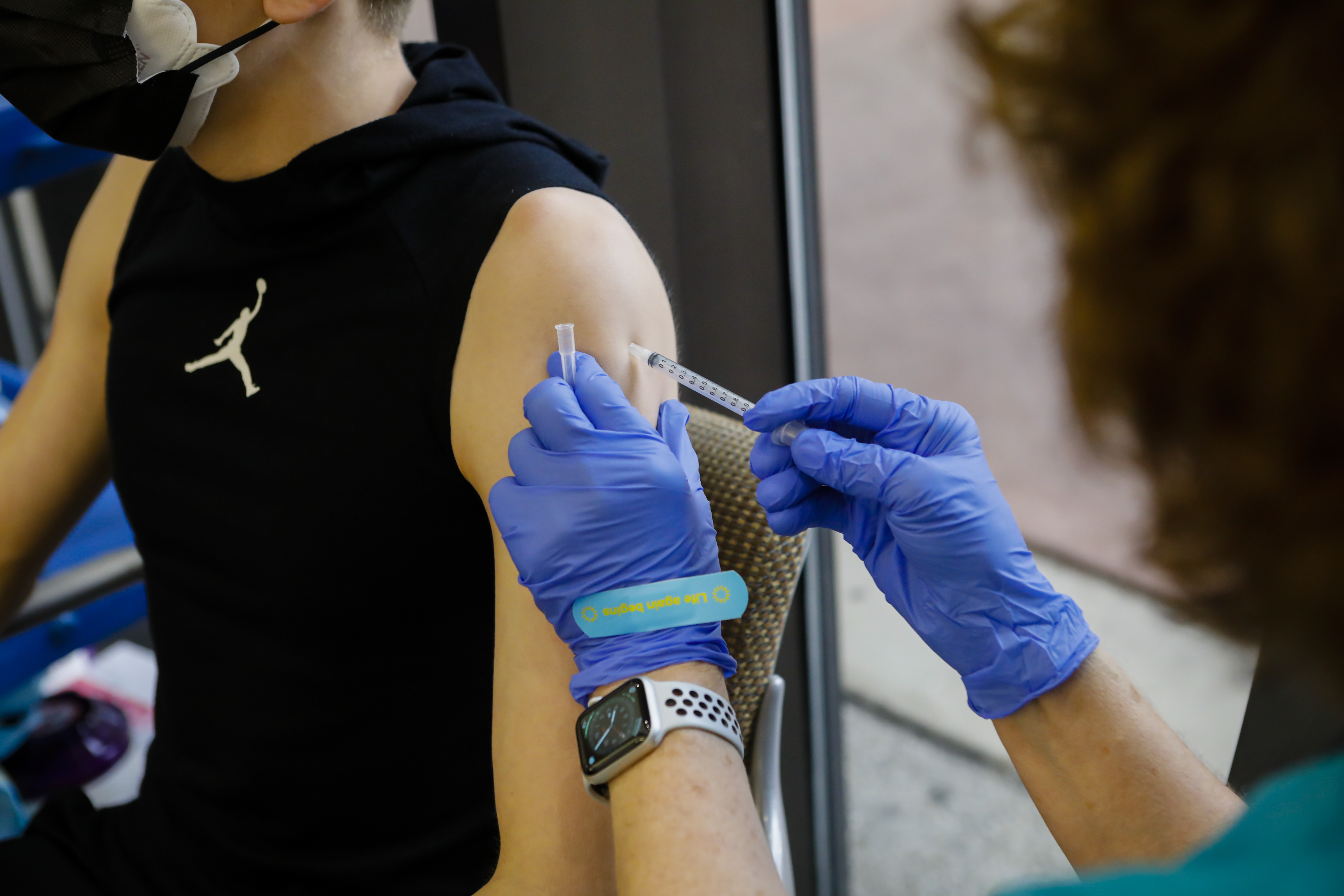 A health care worker administers a dose of the Pfizer-BioNTech vaccine to a teenager at Holtz Children’s Hospital in Miami.