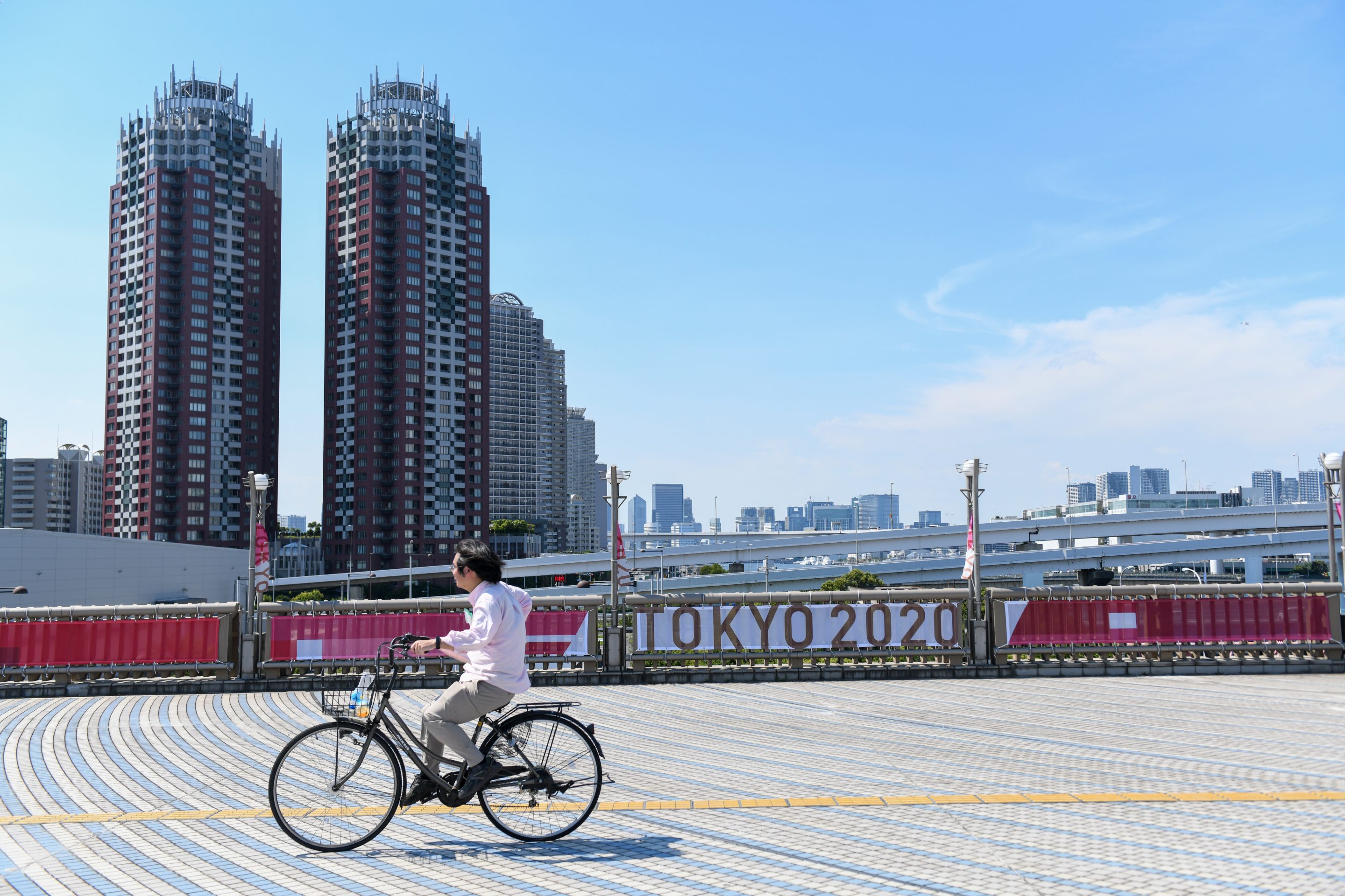 A bicyclist travels past a banner for the Tokyo 2020 Olympic Games on Yume-no-Ohashi Bridge in Tokyo, Japan on July 22, 2021.