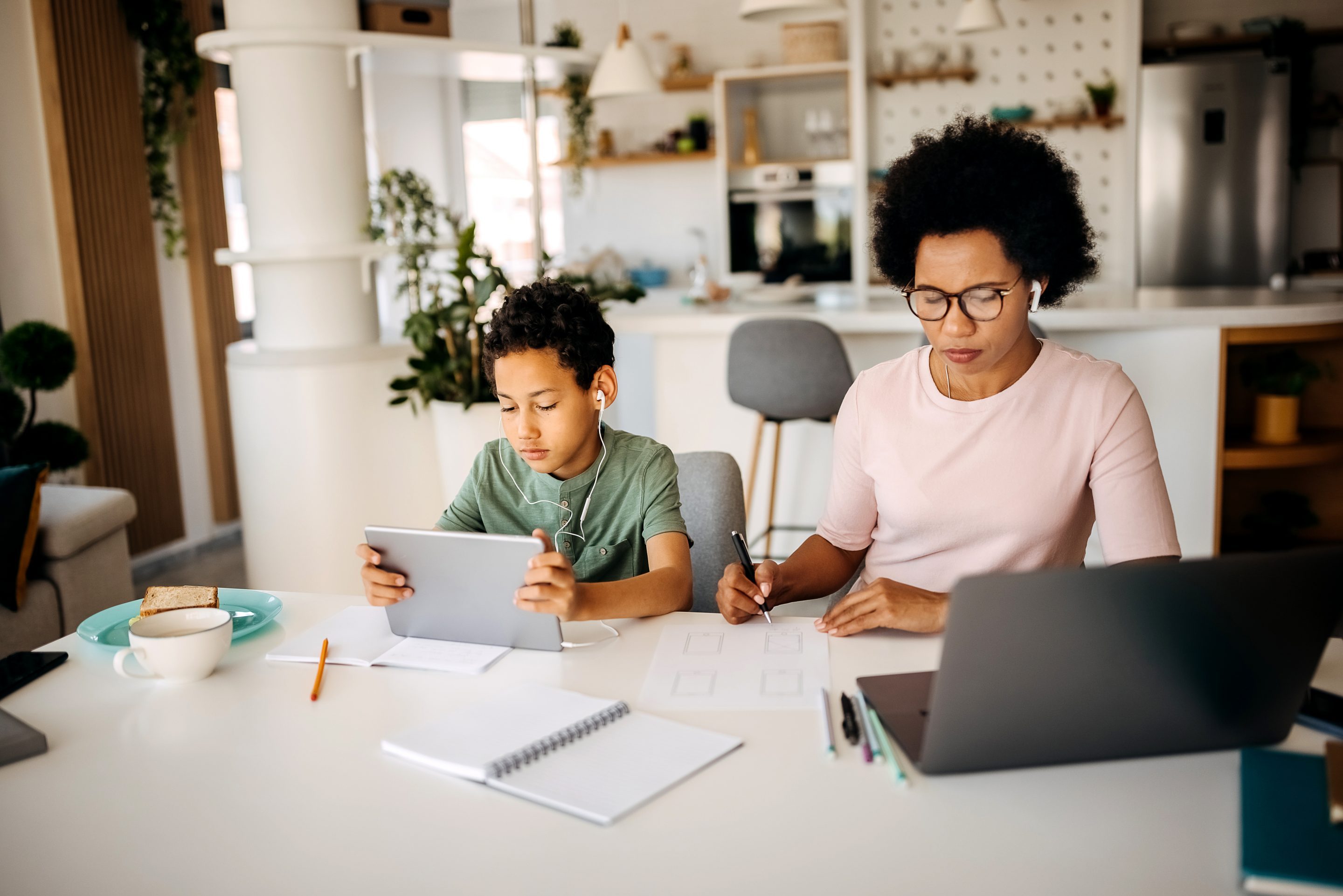 woman working on laptop with child sitting next to her.