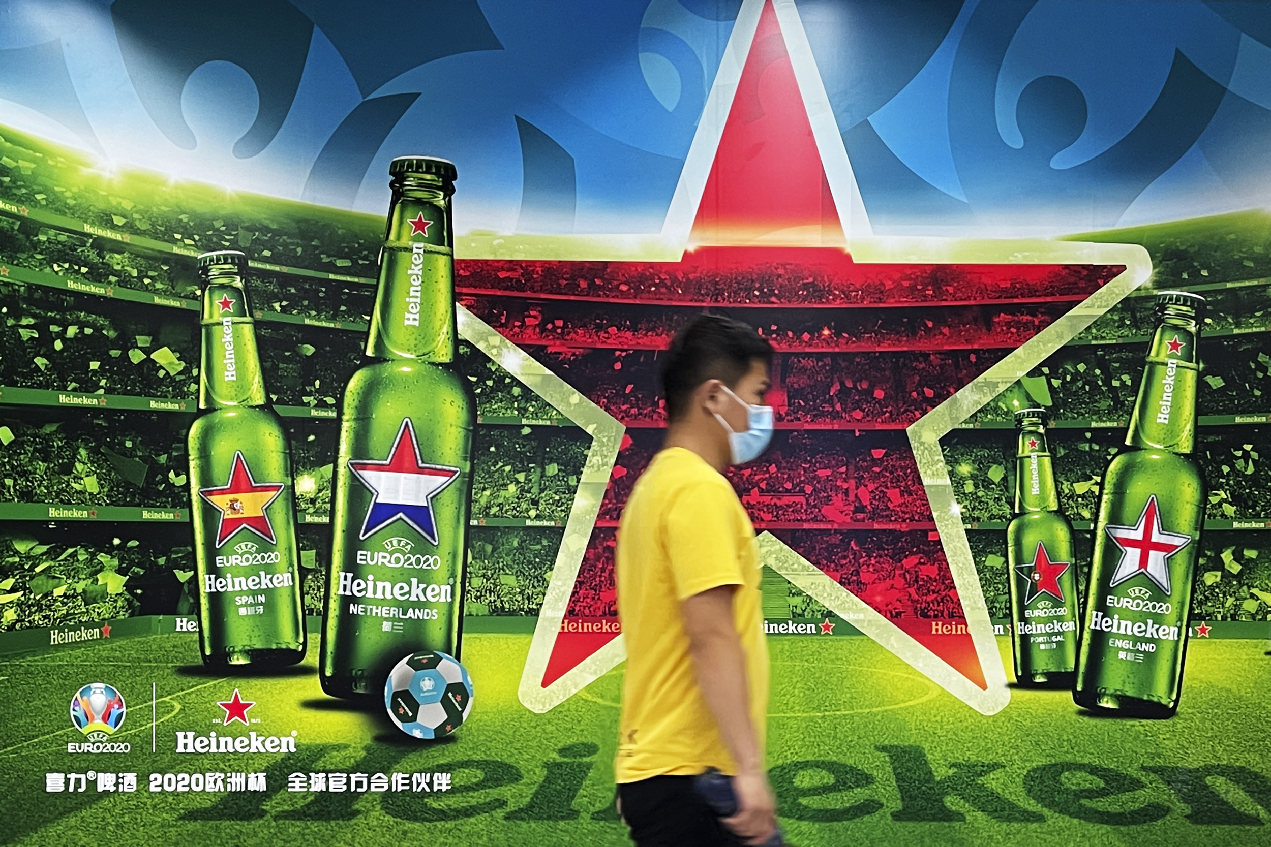 A man walks past an advertisement for Heineken beer at a subway station on July 3, 2021 in Beijing, China.