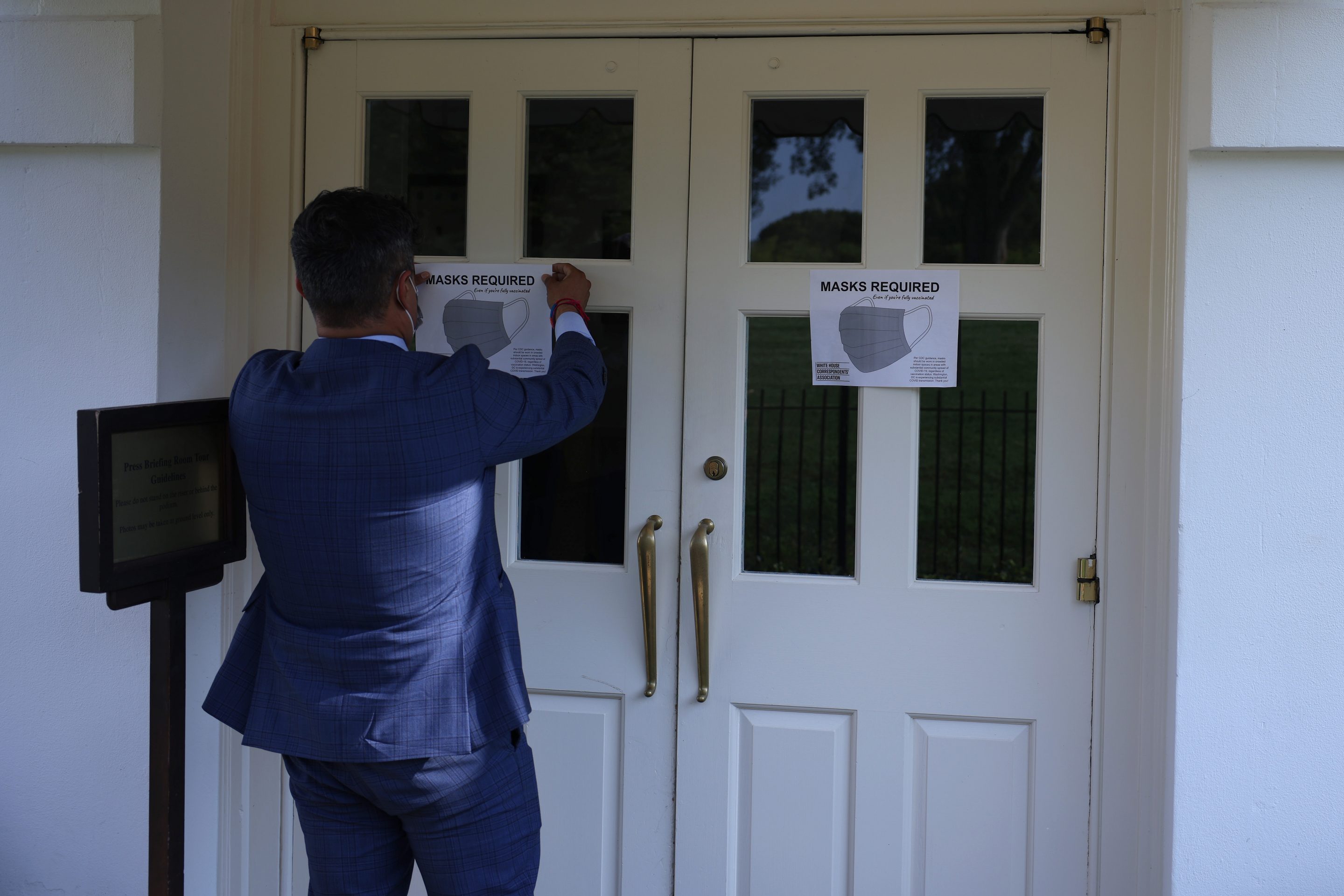 Fin Gomez, a journalist with CBS News and White House Correspondents Association (WHCA) board member, replaces signs for mask-wearing guidance around the James Brady Press Briefing Room at the White House on July 27, 2021 in Washington, DC.