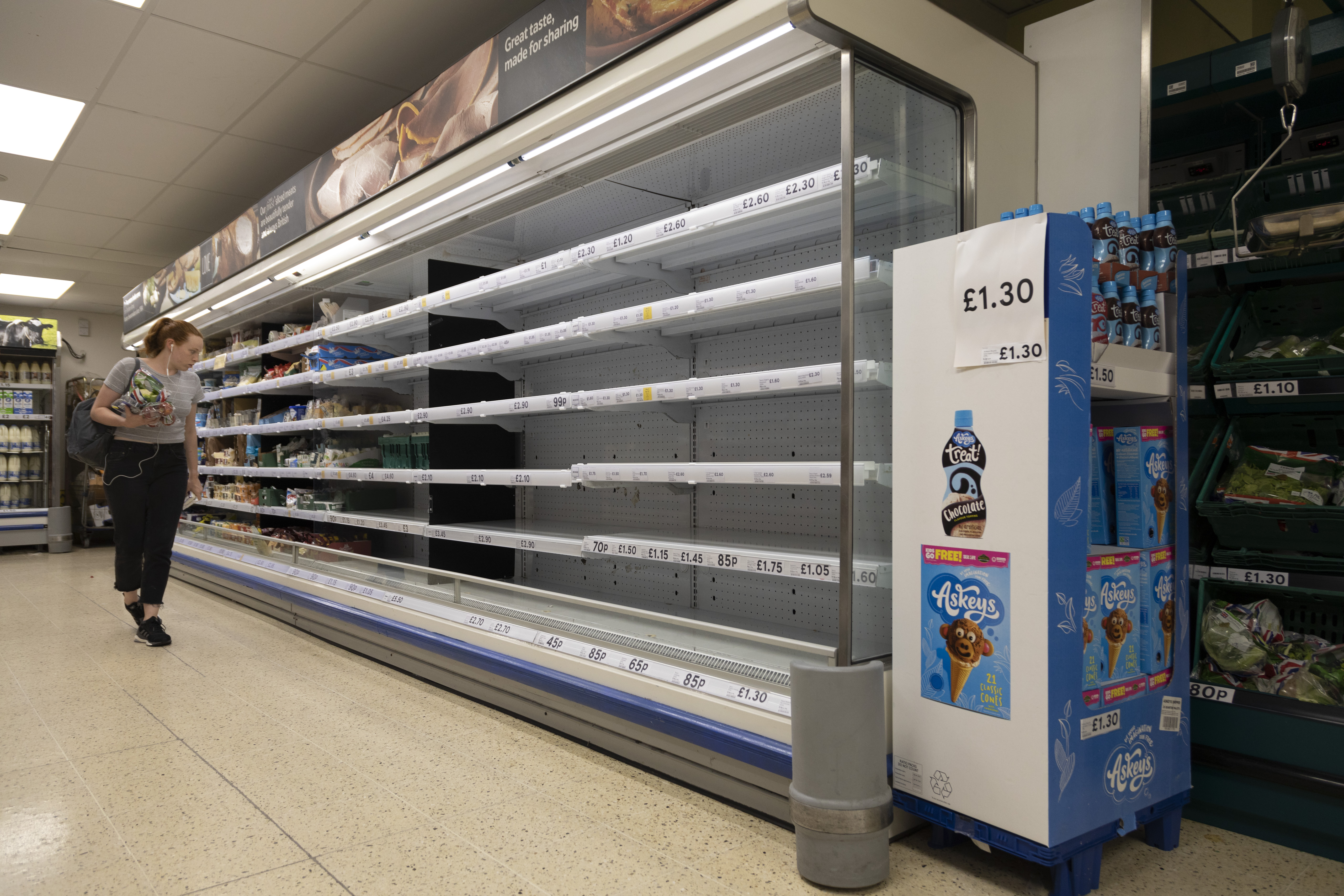 A shopper stands by empty shelves with no stock on them in a Tesco on 22nd July, 2021 in Leeds, United Kingdom.