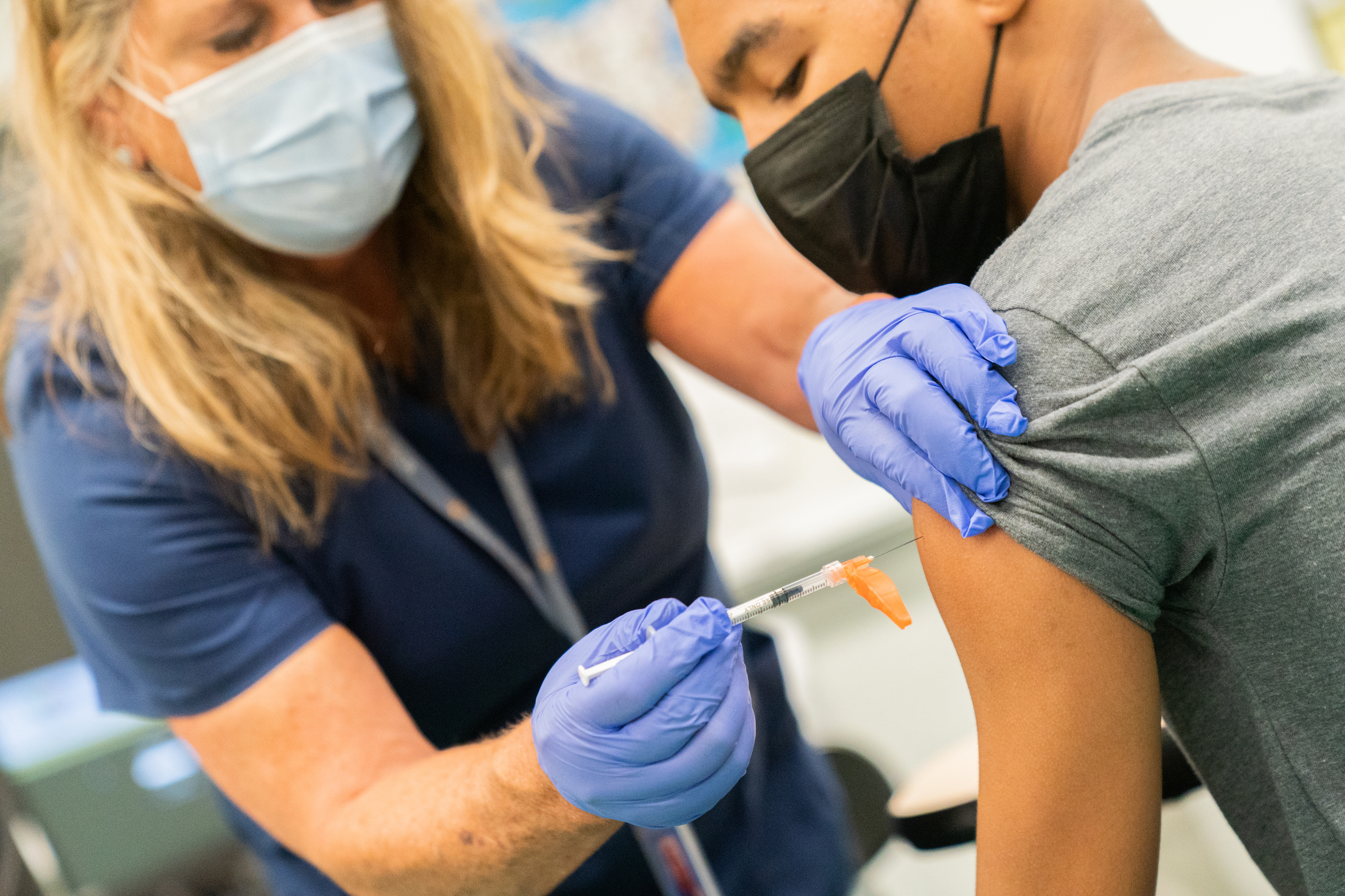 A healthcare worker administers a dose of the Pfizer-BioNTech Covid-19 vaccine to a student during a 'Vax To School' campaign event at a high school in the Staten Island borough of New York on Aug. 10, 2021.