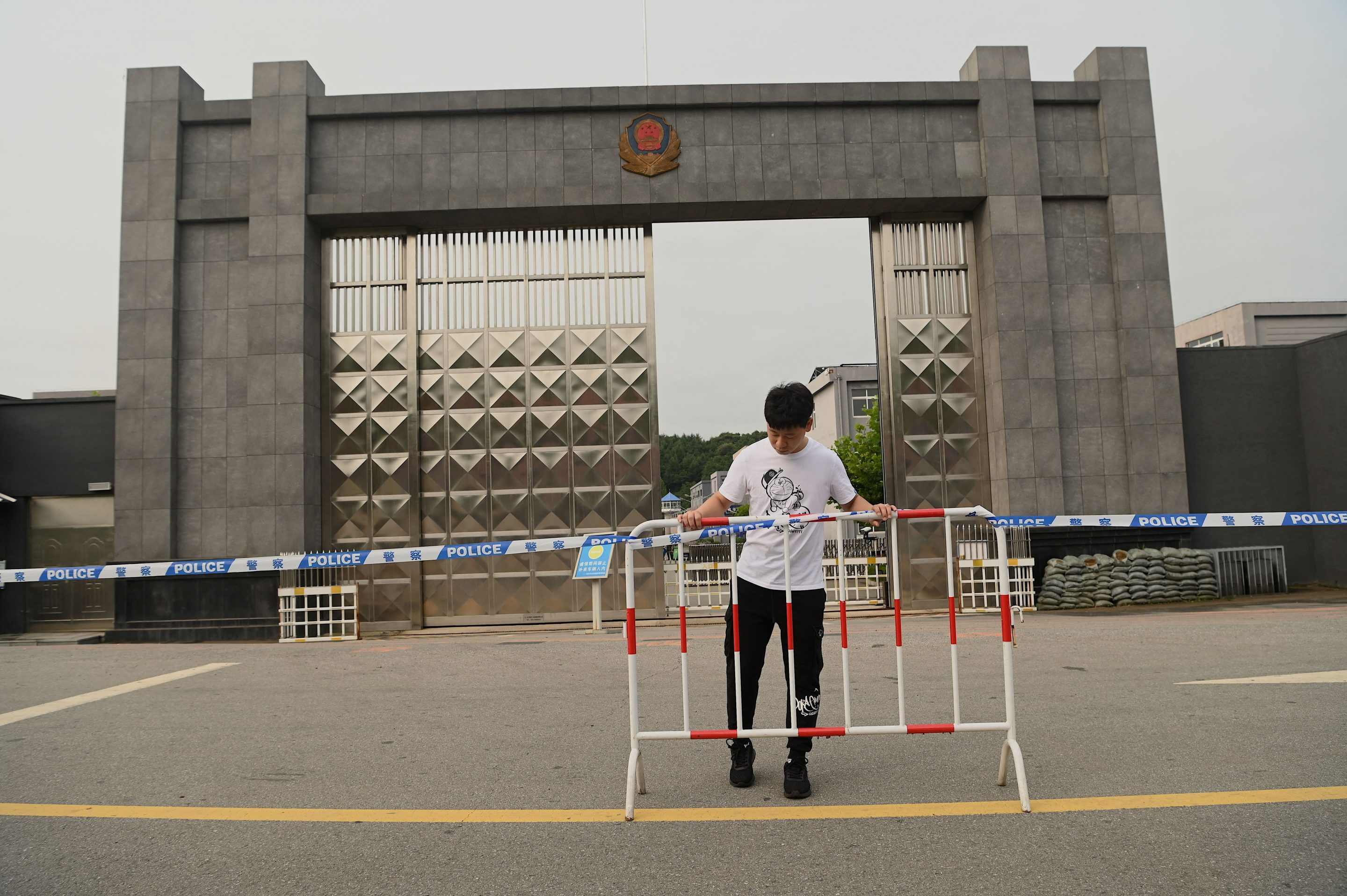 A man puts police tape in front of the Dandong city detention center where Canadian businessman Michael Spavor is being held on spying charges in the border city of Dandong in China's northeast Liaoning province on August 11, 2021.