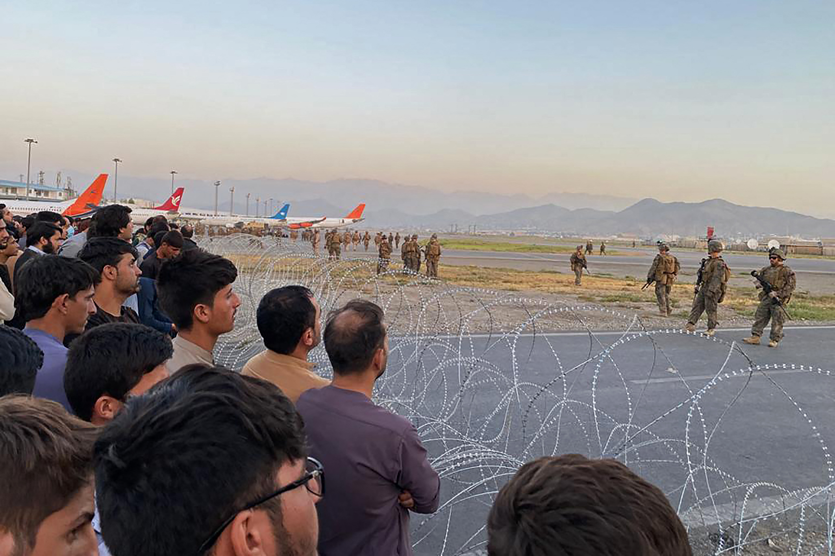 Afghans crowd at Kabul's airport as U.S. soldiers stand guard on August 16, 2021.