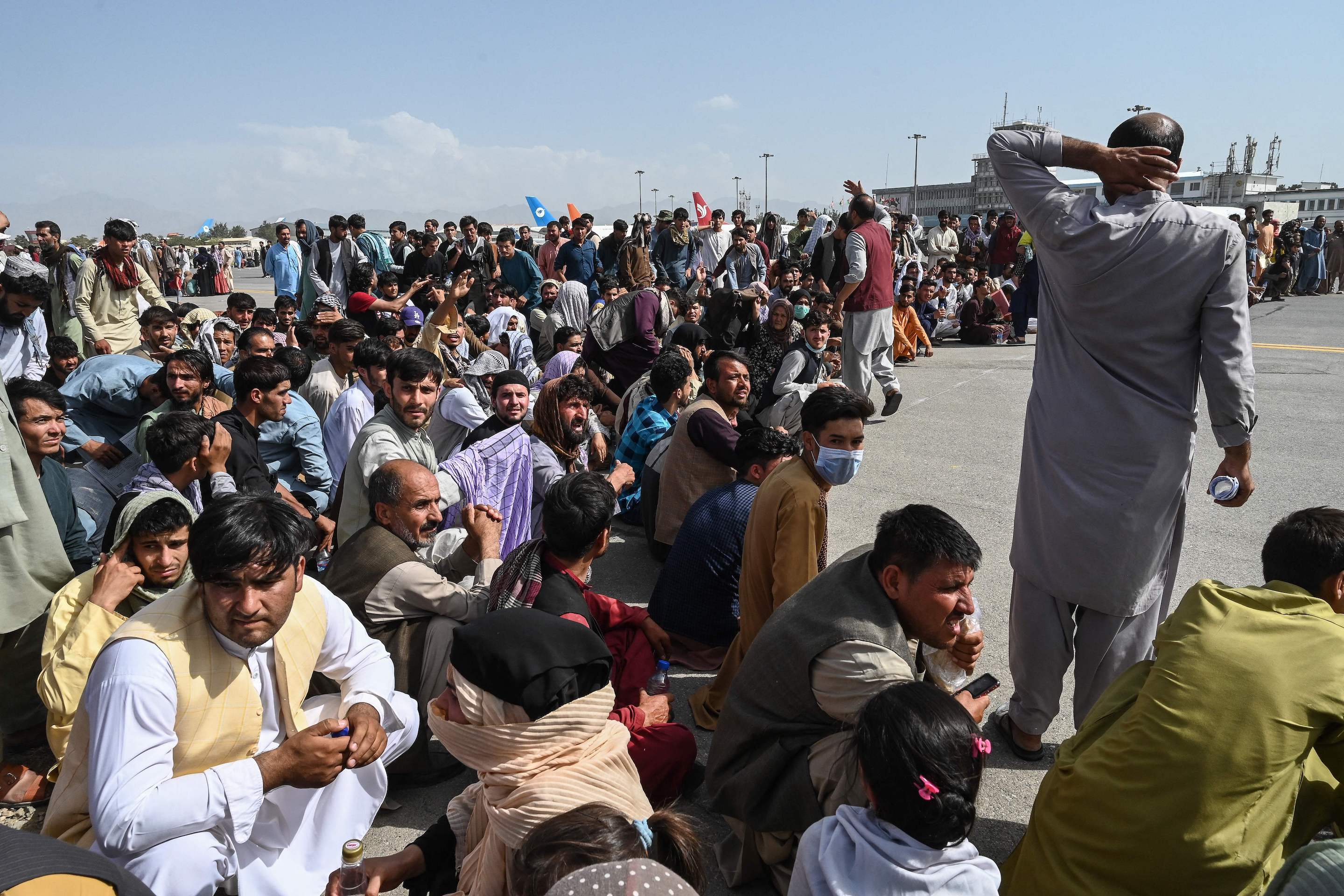 Afghan passengers sit as they wait to leave the Kabul airport in Kabul on August 16, 2021.