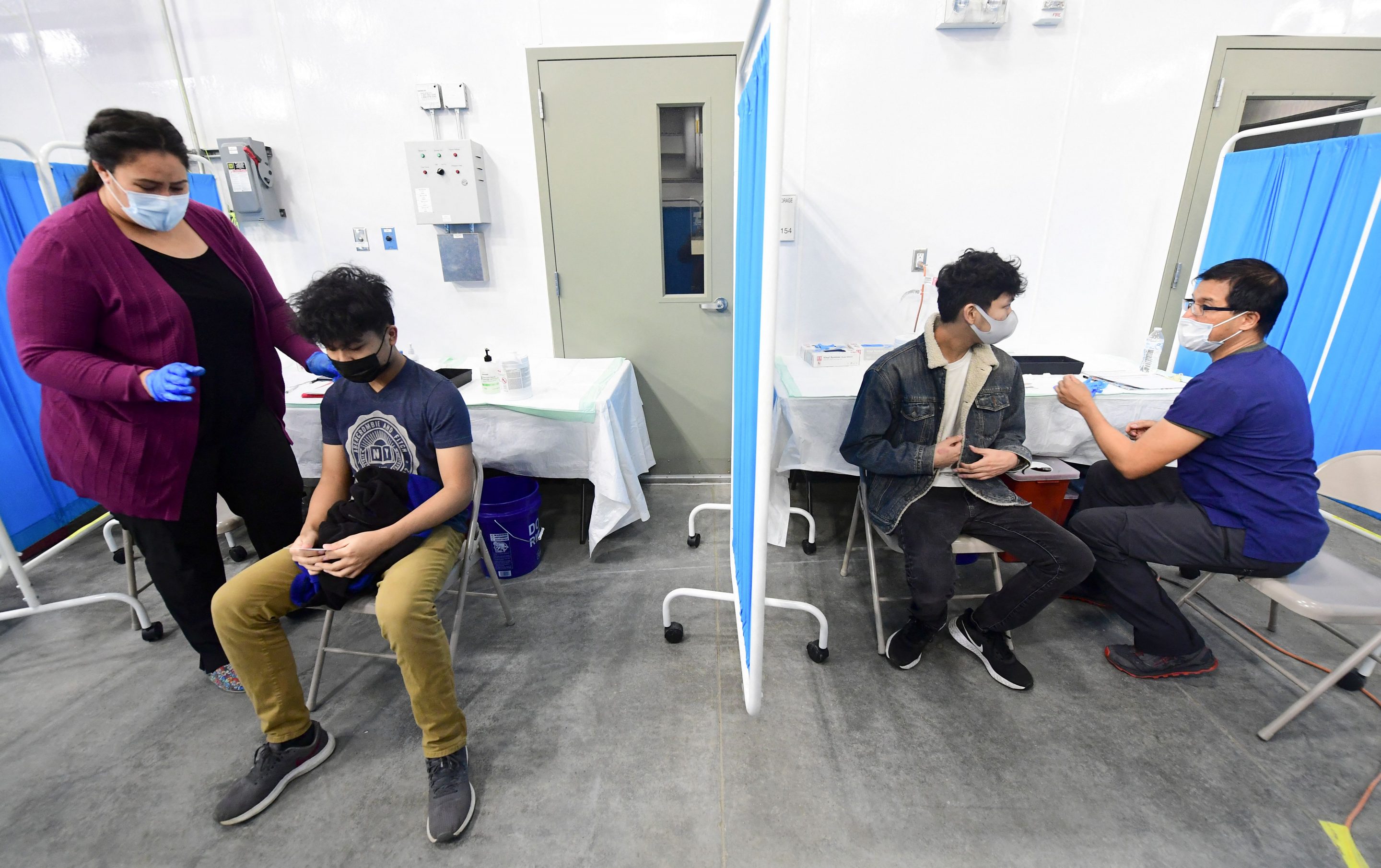 Brothers Ames, 17 (left), and Amiel, 19, receive their first dose of the Pfizer COVID-19 vaccine at the Blood Bank of Alaska in Anchorage, on March 19, 2021. Once a model for vaccinations, Alaska has fallen behind the national vaccination rate and is now facing its worst surge of COVID cases.