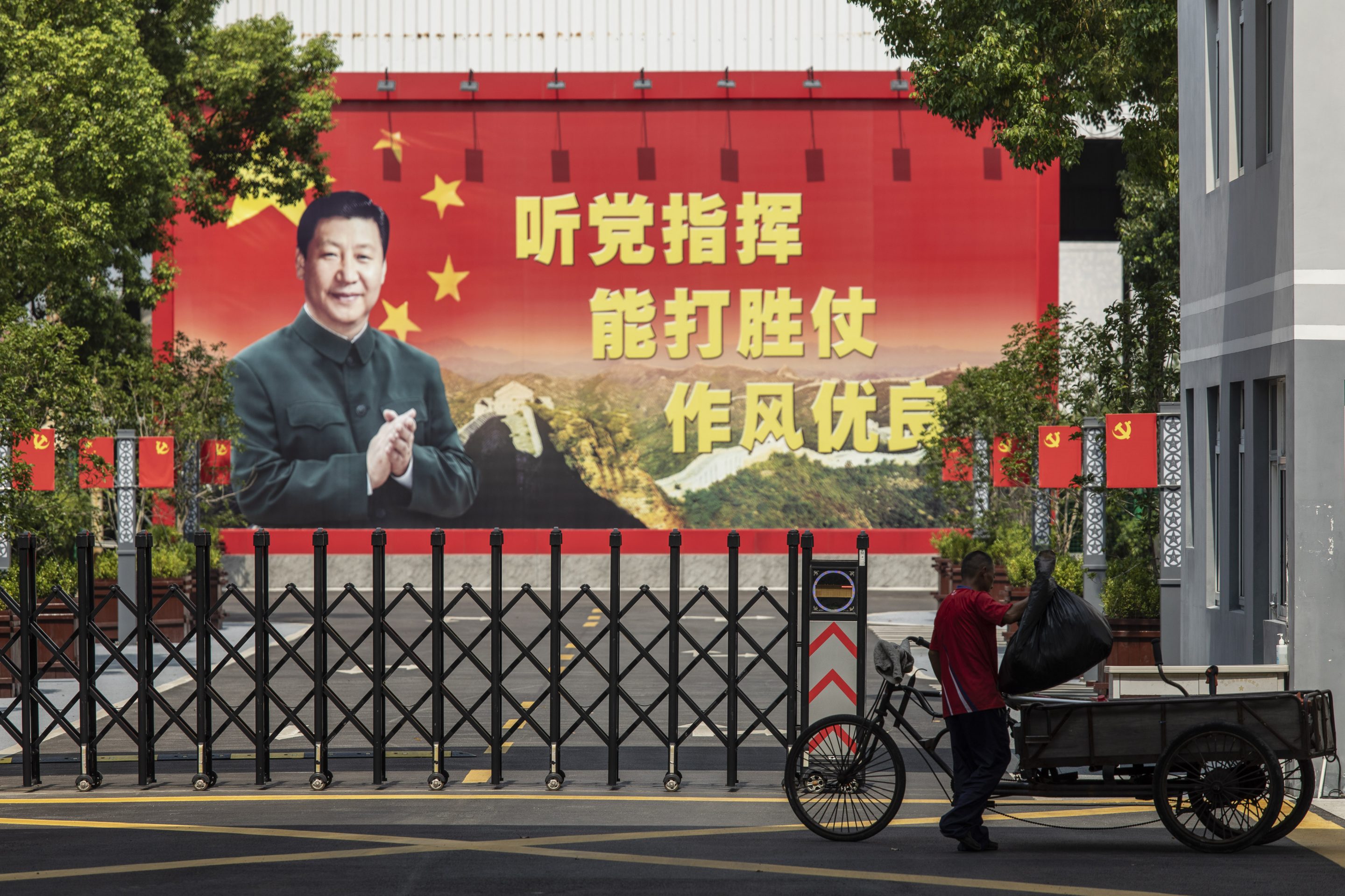 A man places a bag of trash into his rickshaw in front of a compound displaying a billboard featuring China's President Xi Jinping in Shanghai, China, on Aug. 30, 2021.