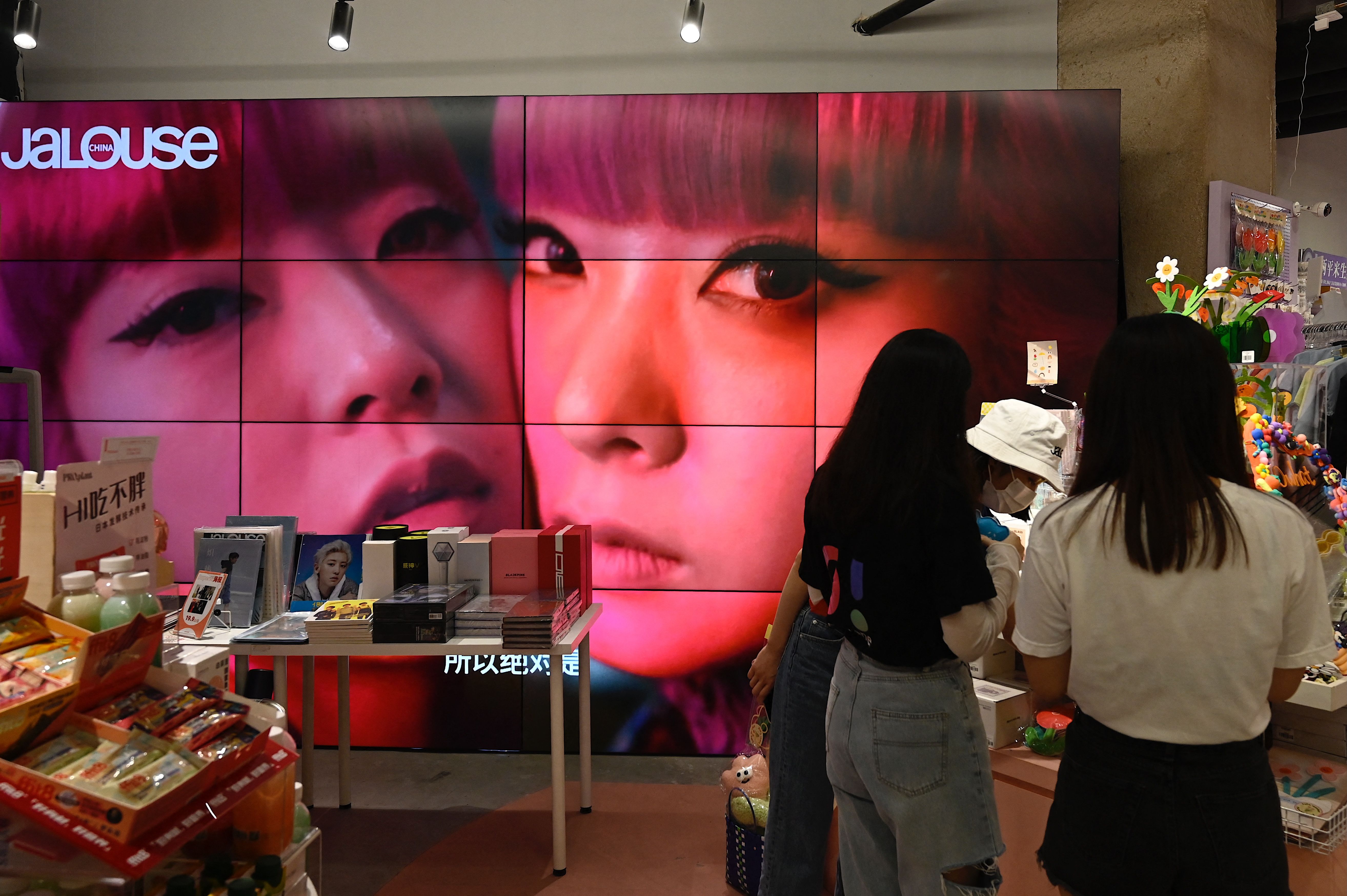 A screen shows a video of overseas celebrity idols at a fan merchandise store at a shopping mall in Beijing on September 2, 2021.