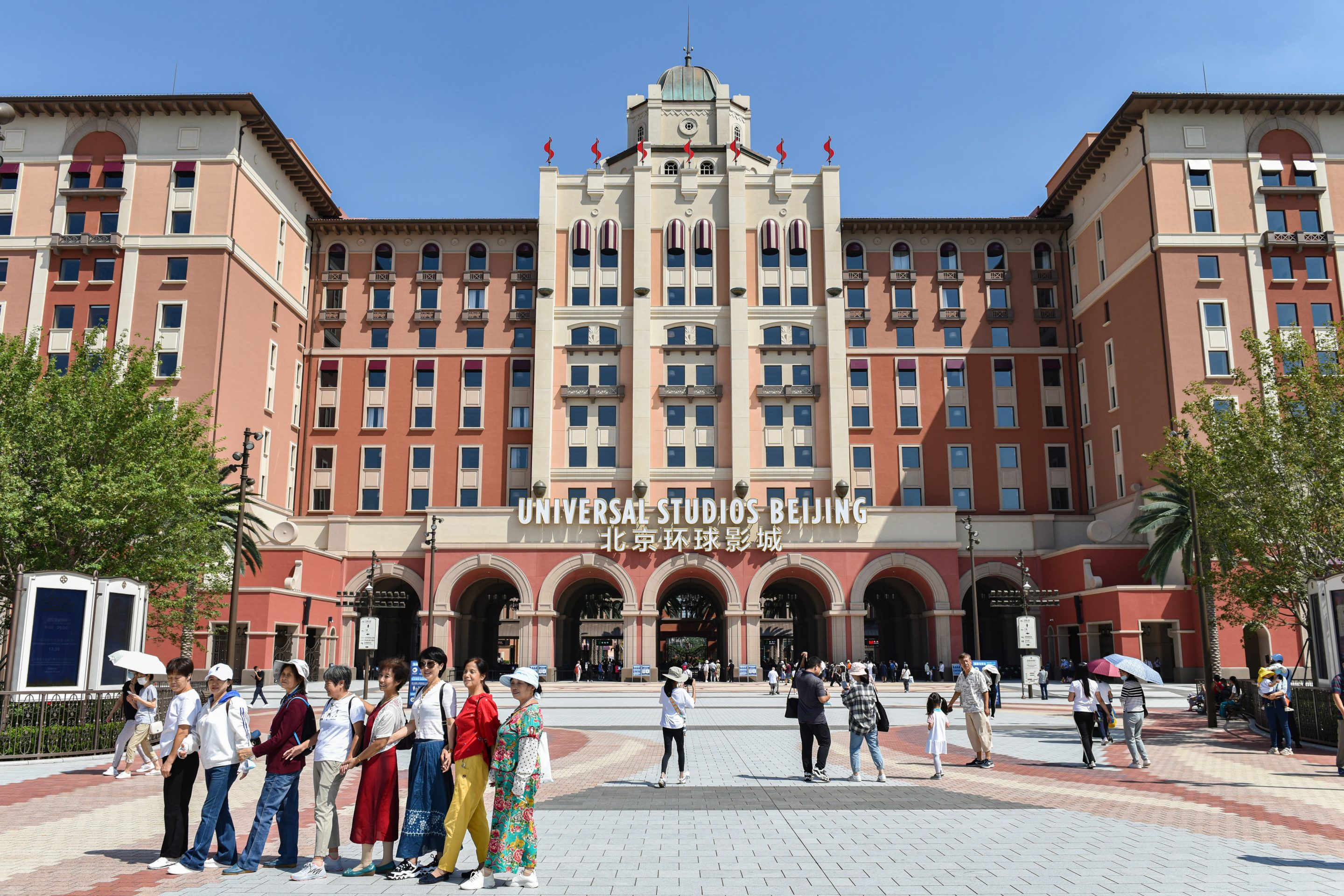 Tourists pose for pictures in front of Beijing Universal Studios.